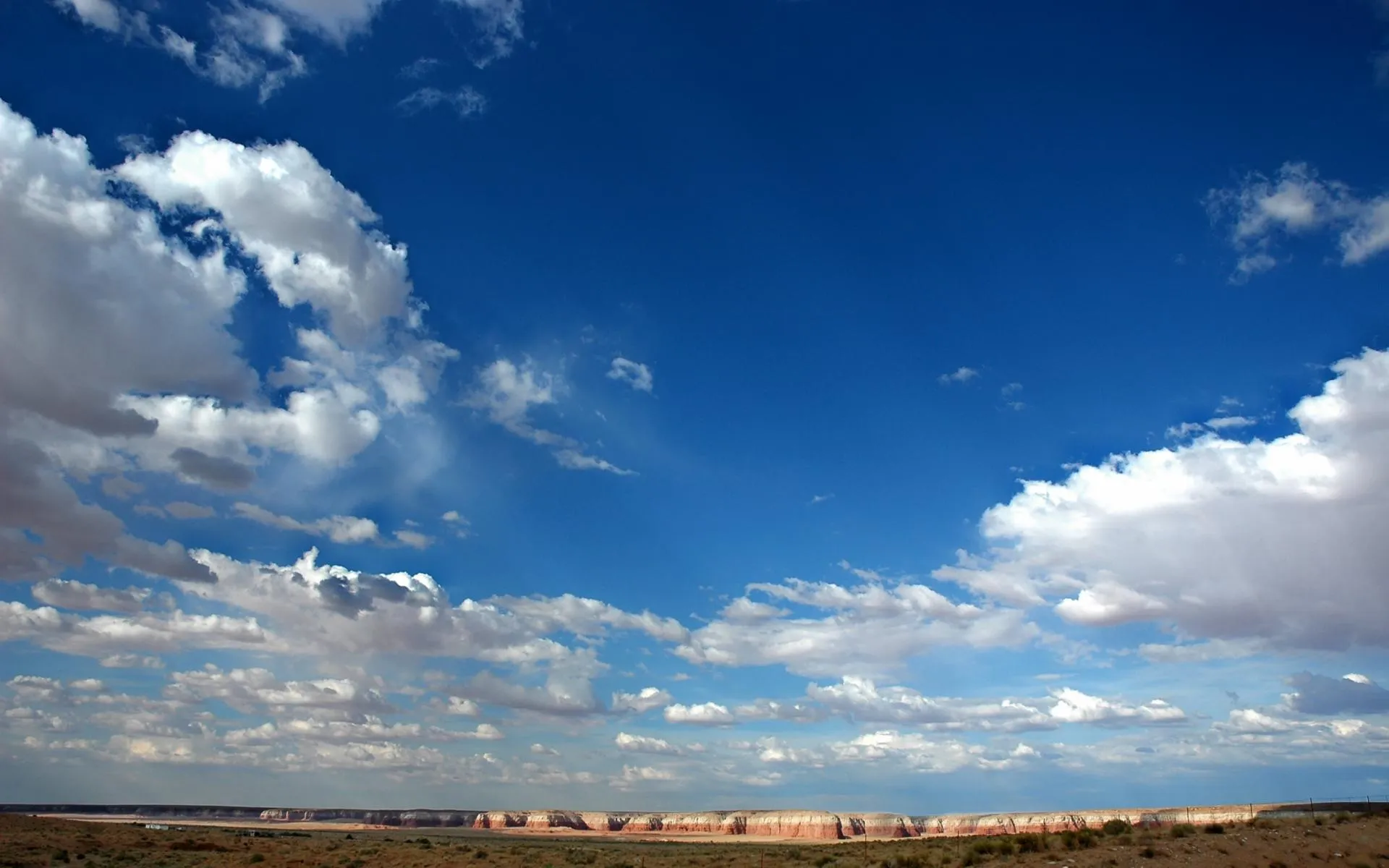 Clear Blue Sky with Large Puffy White Clouds Over Field