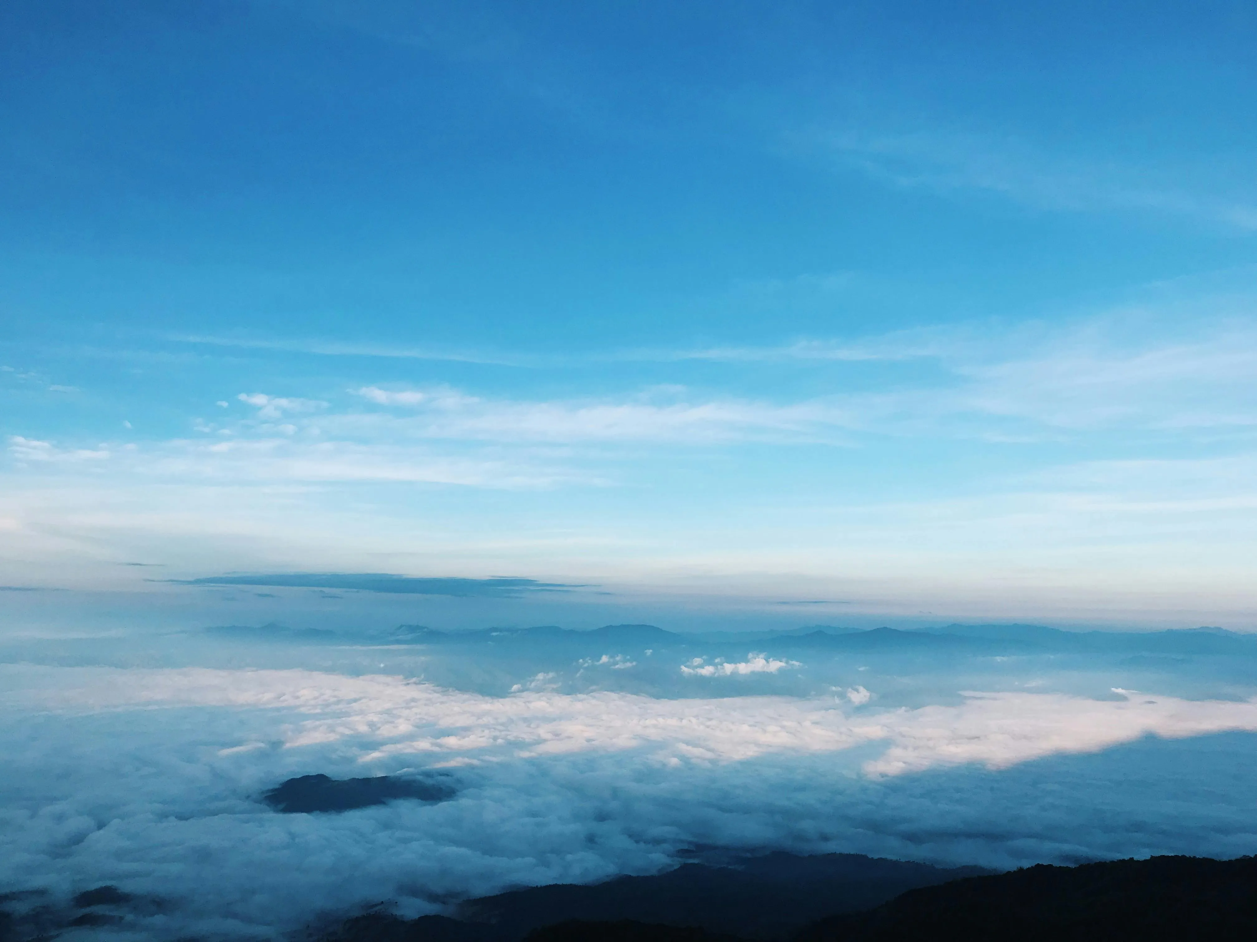 Clear Blue Sky with Light Clouds Above Mountain Range