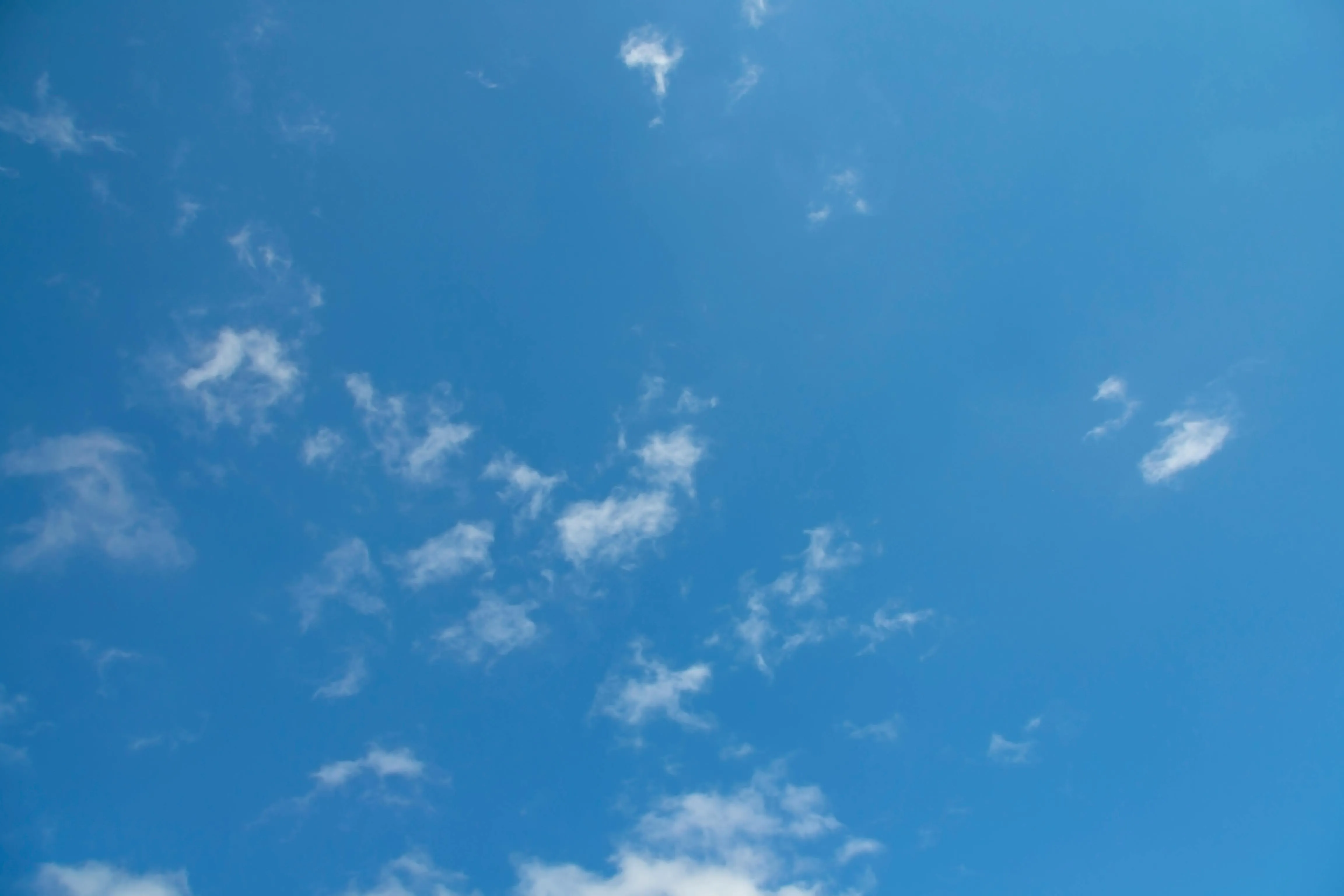 Clear Blue Sky with Scattered White Clouds Above Image