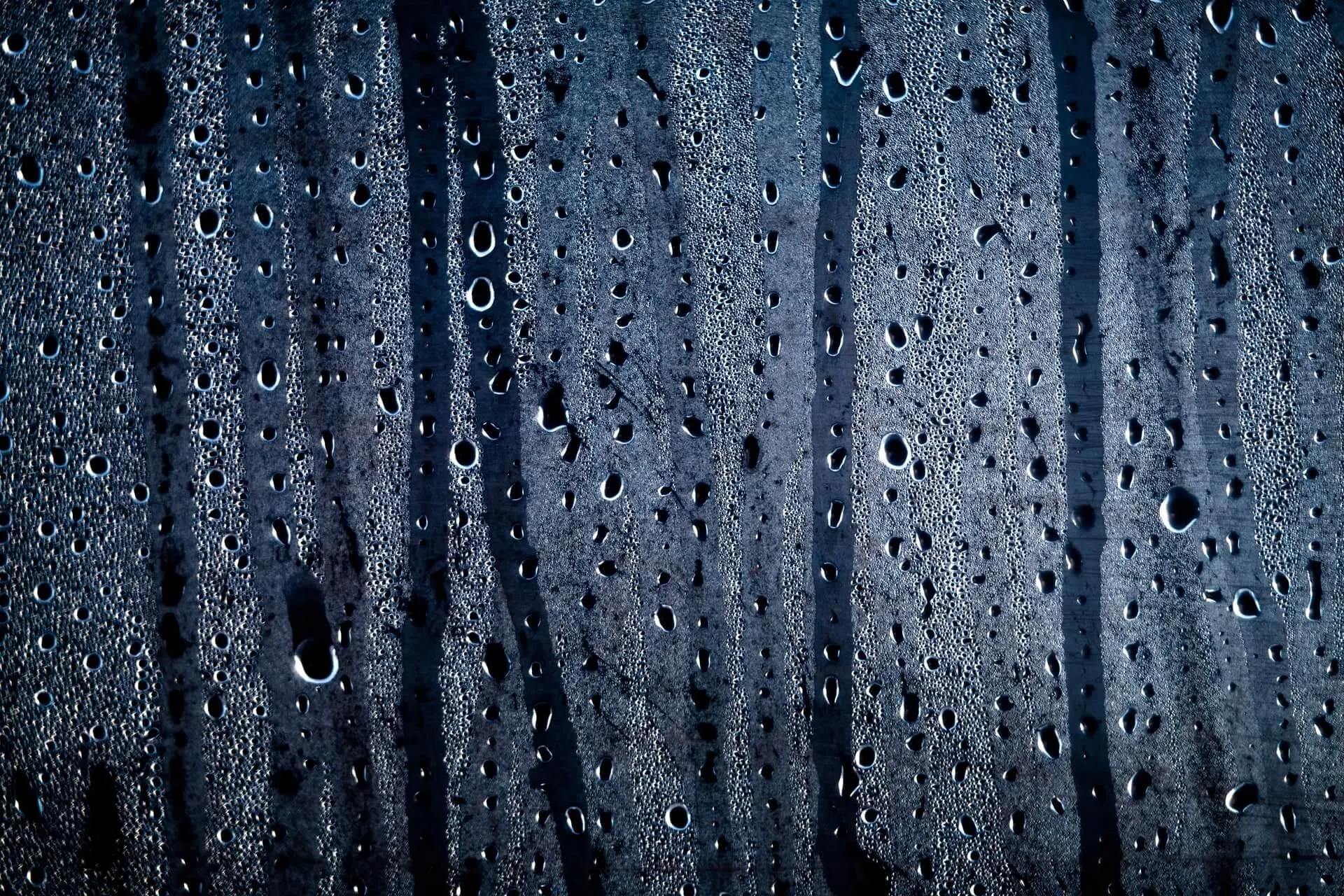 Closeup of Dark Blue Wet Window with Raindrops Wallpaper