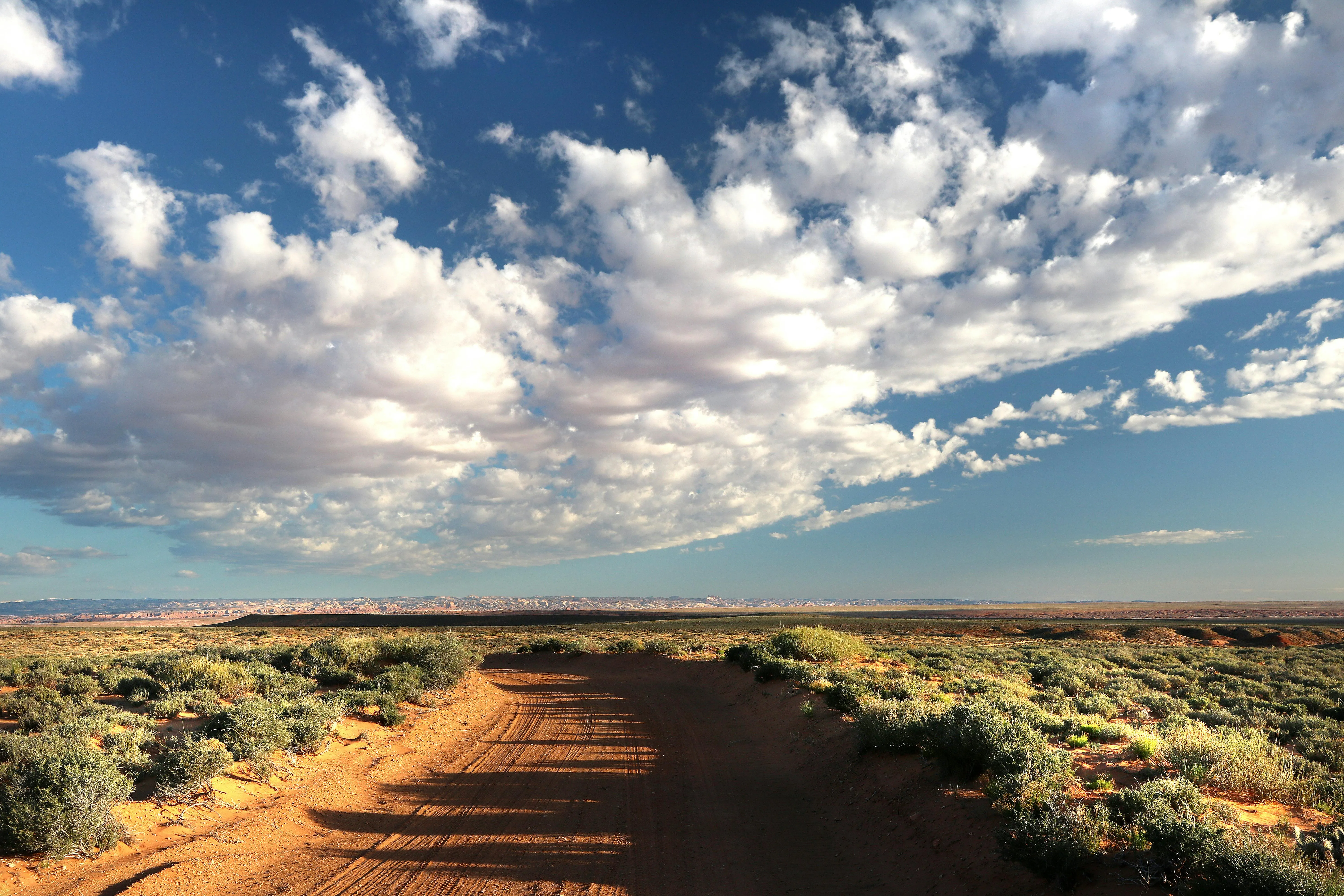 Cloud Filled Sky Over Dirt Path Through Grassland Image