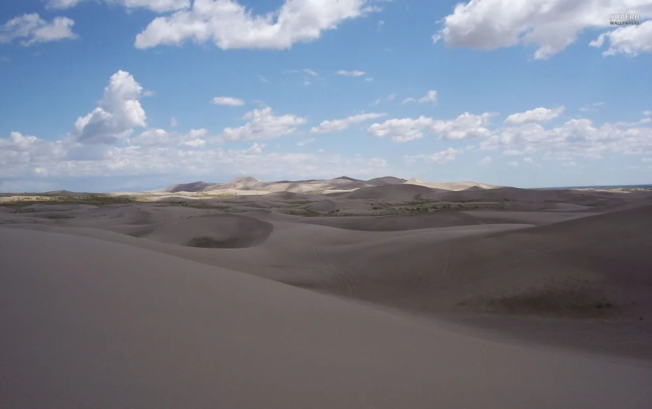 Clouds Over Sandy Desert Landscape with Bright Blue Sky