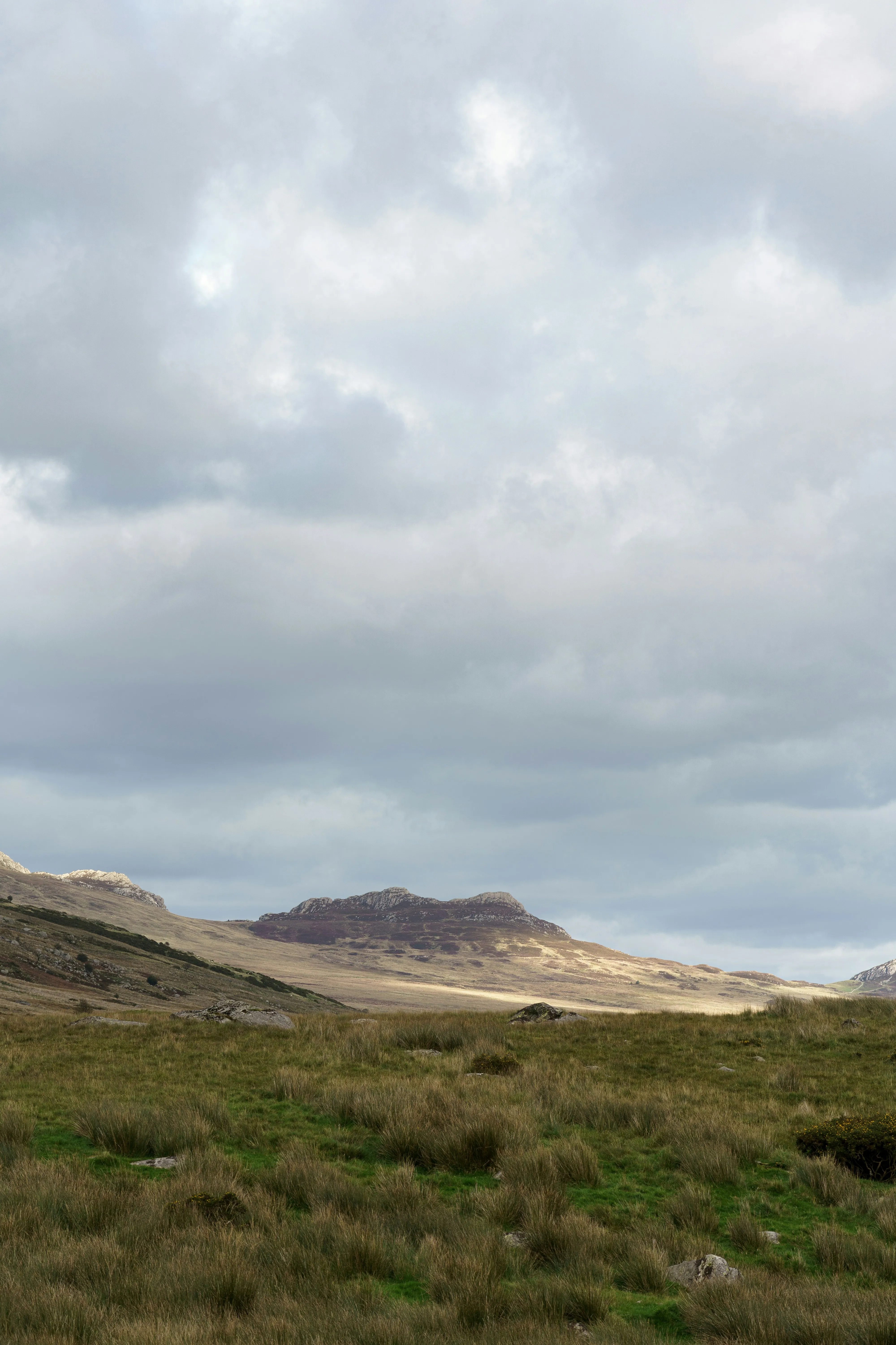 Cloudy Sky Over Rolling Hills and Open Field Landscape