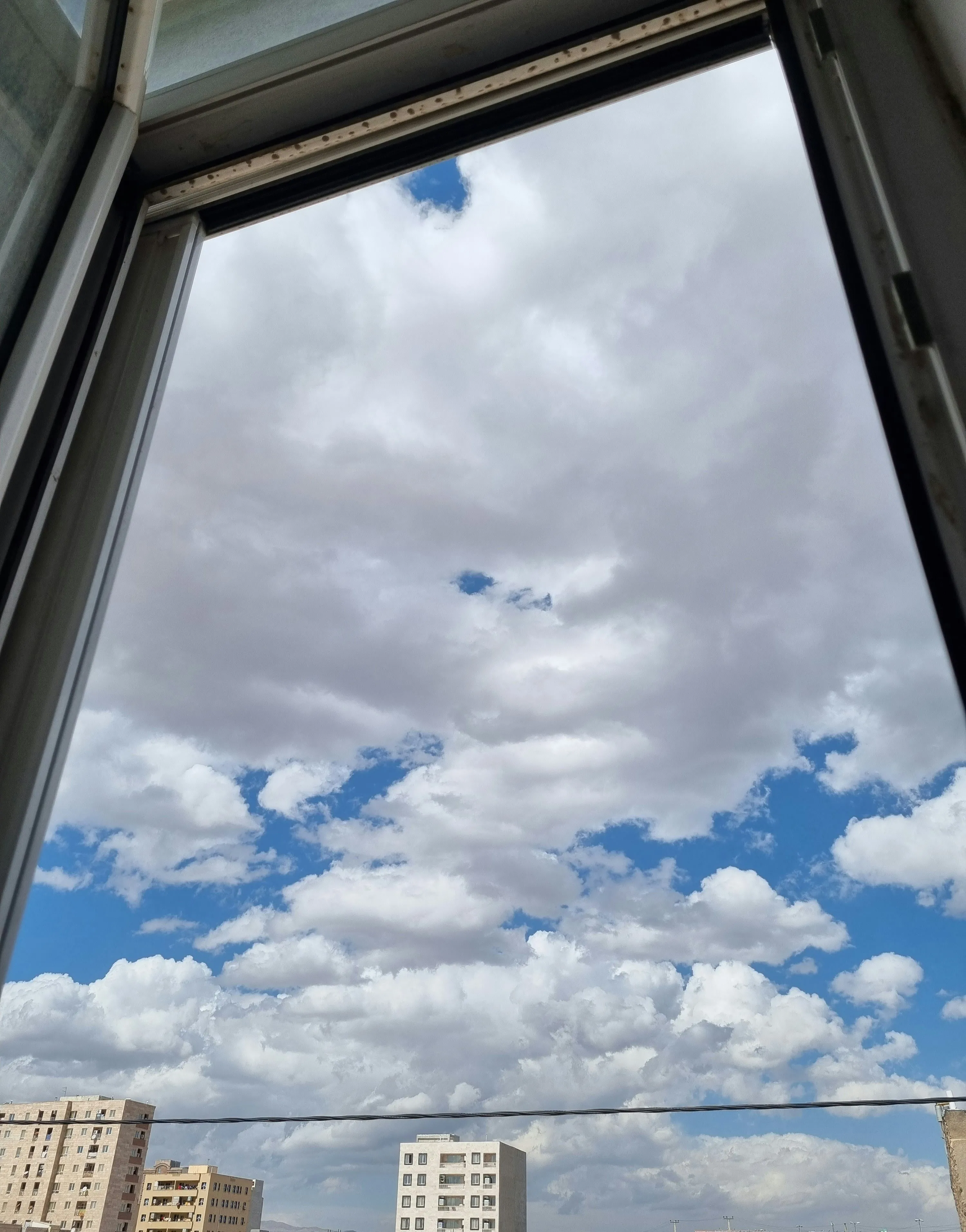 Cloudy Sky Seen From a Window with Urban Buildings Image