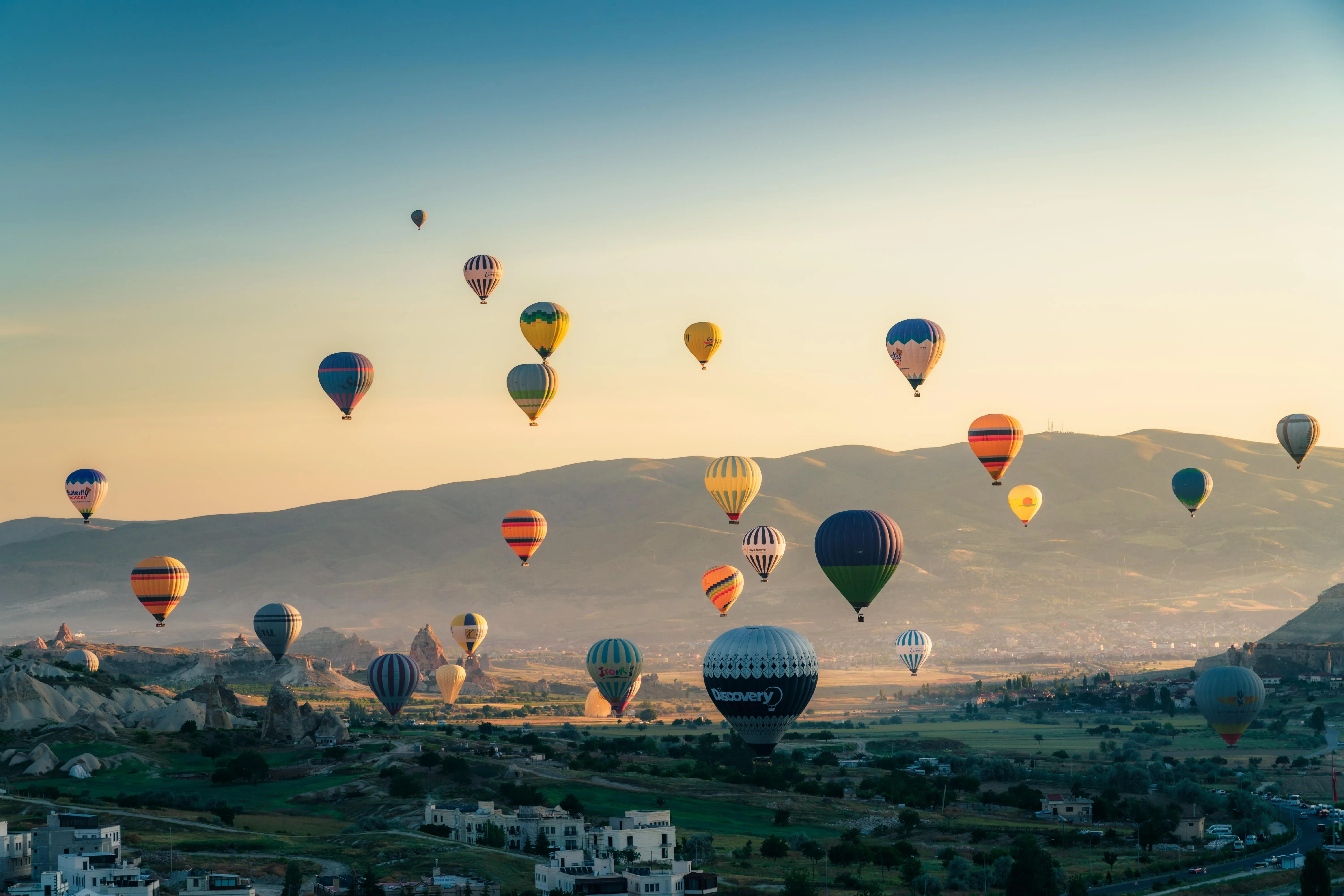 Colorful Balloons Soaring Above Hills During Sunrise