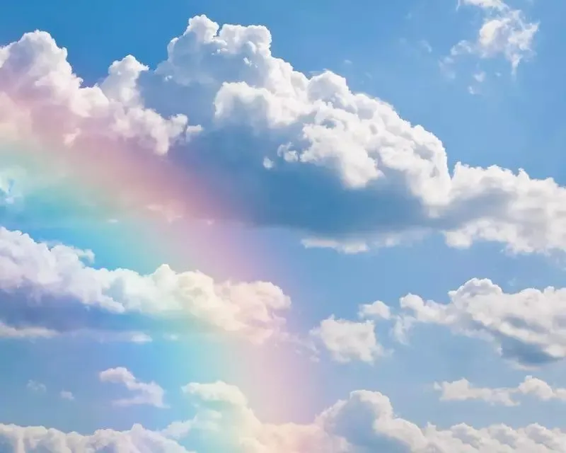 Colorful Rainbow Arcing Over White Fluffy Clouds in Sky