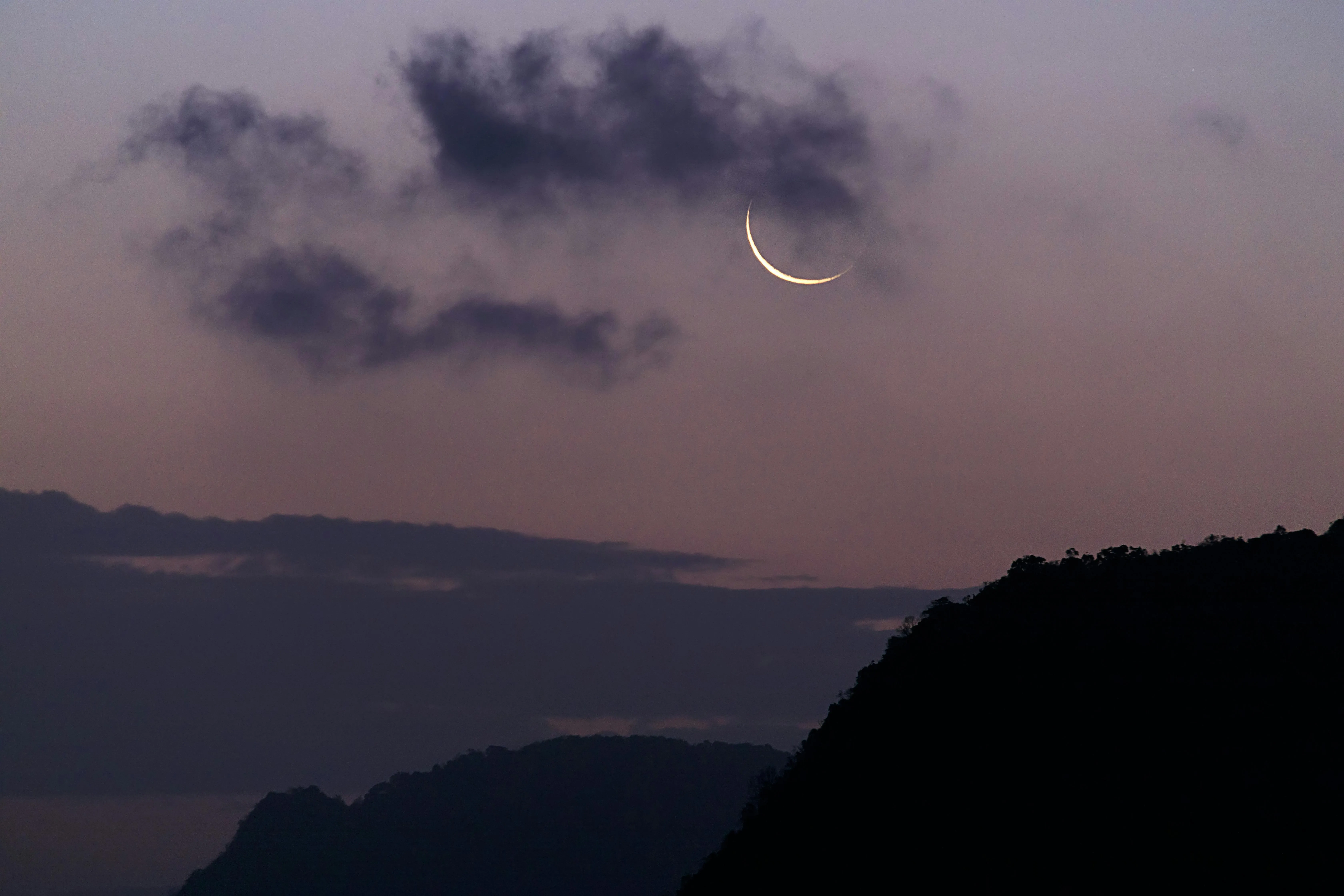 Crescent Moon Shining Above Silhouetted Hills at Twilight