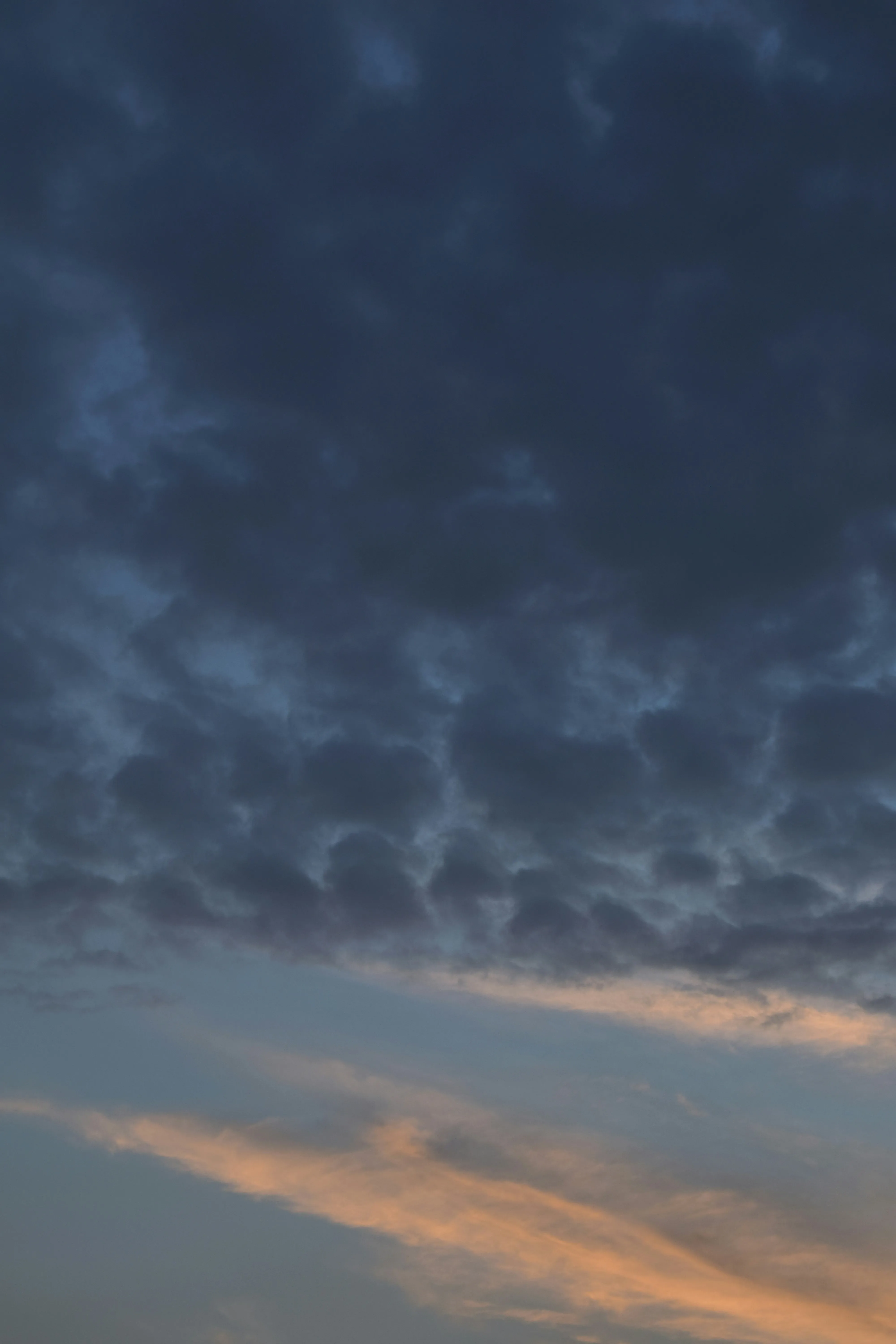Dark Cloud Formation with Orange Sunset Light on Horizon