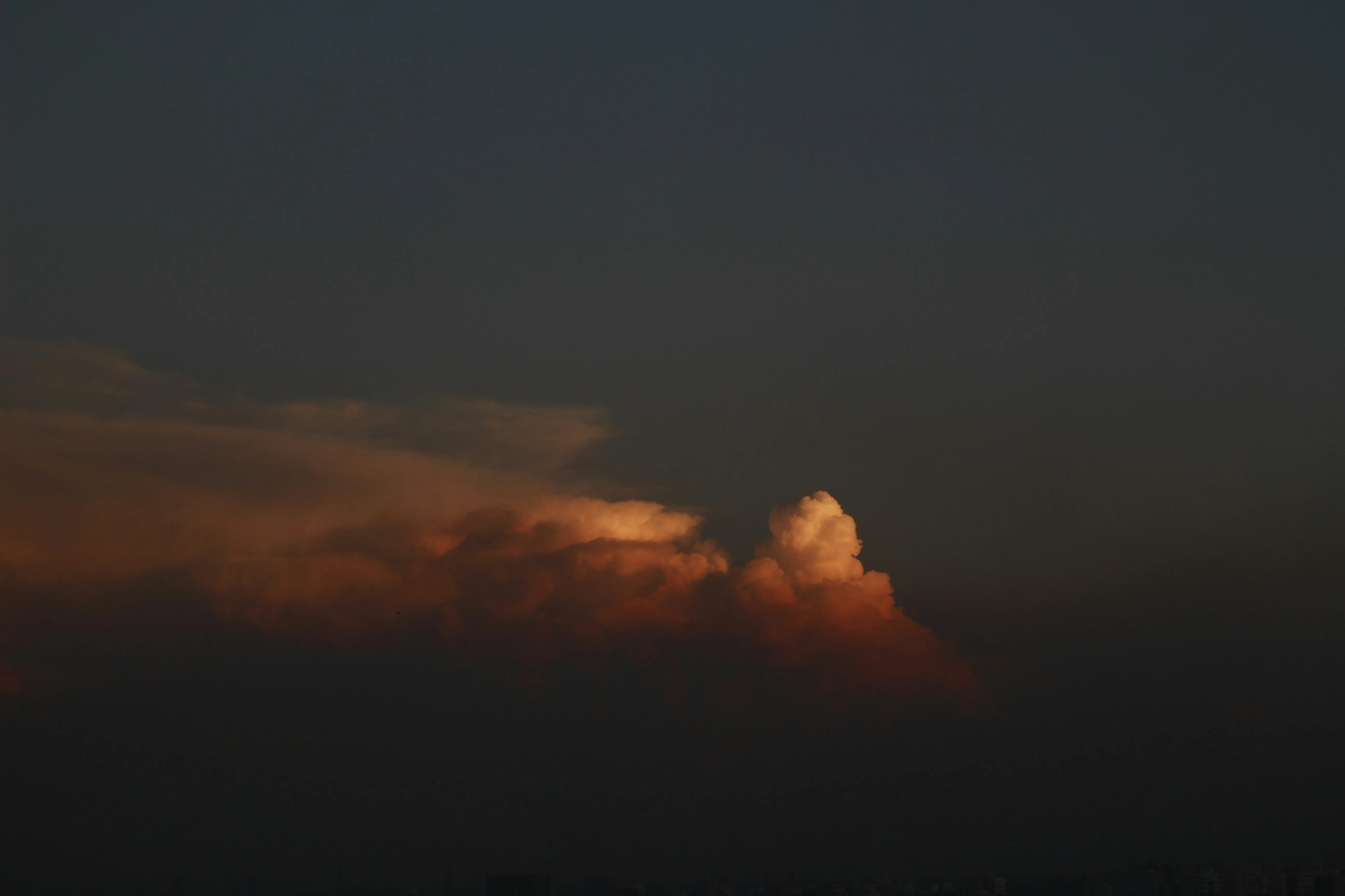Dark Clouds Glowing with Orange Light at Sunset Horizon