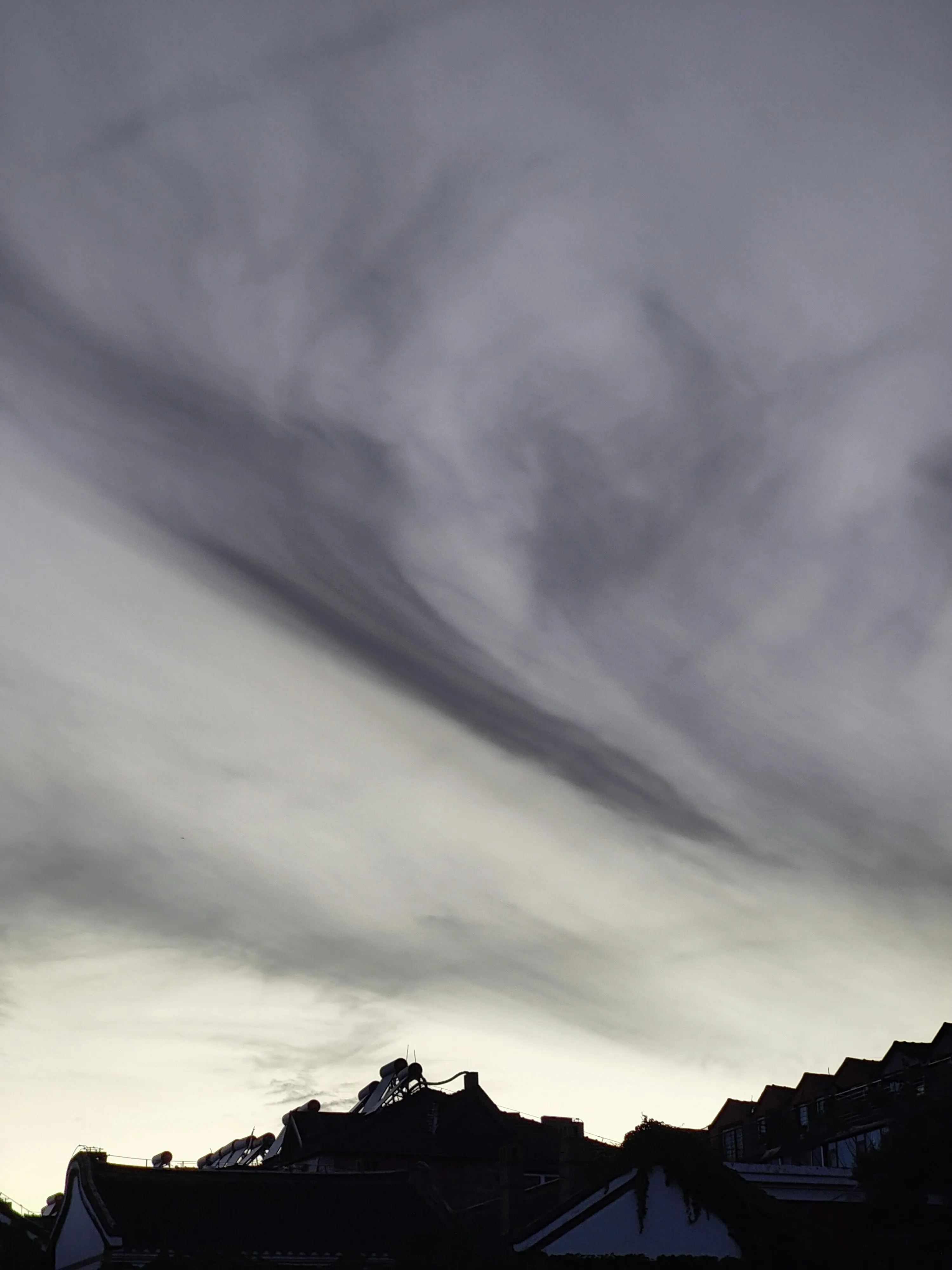 Dark Silhouette of Mountain with Moody Sky and Cloud Streaks