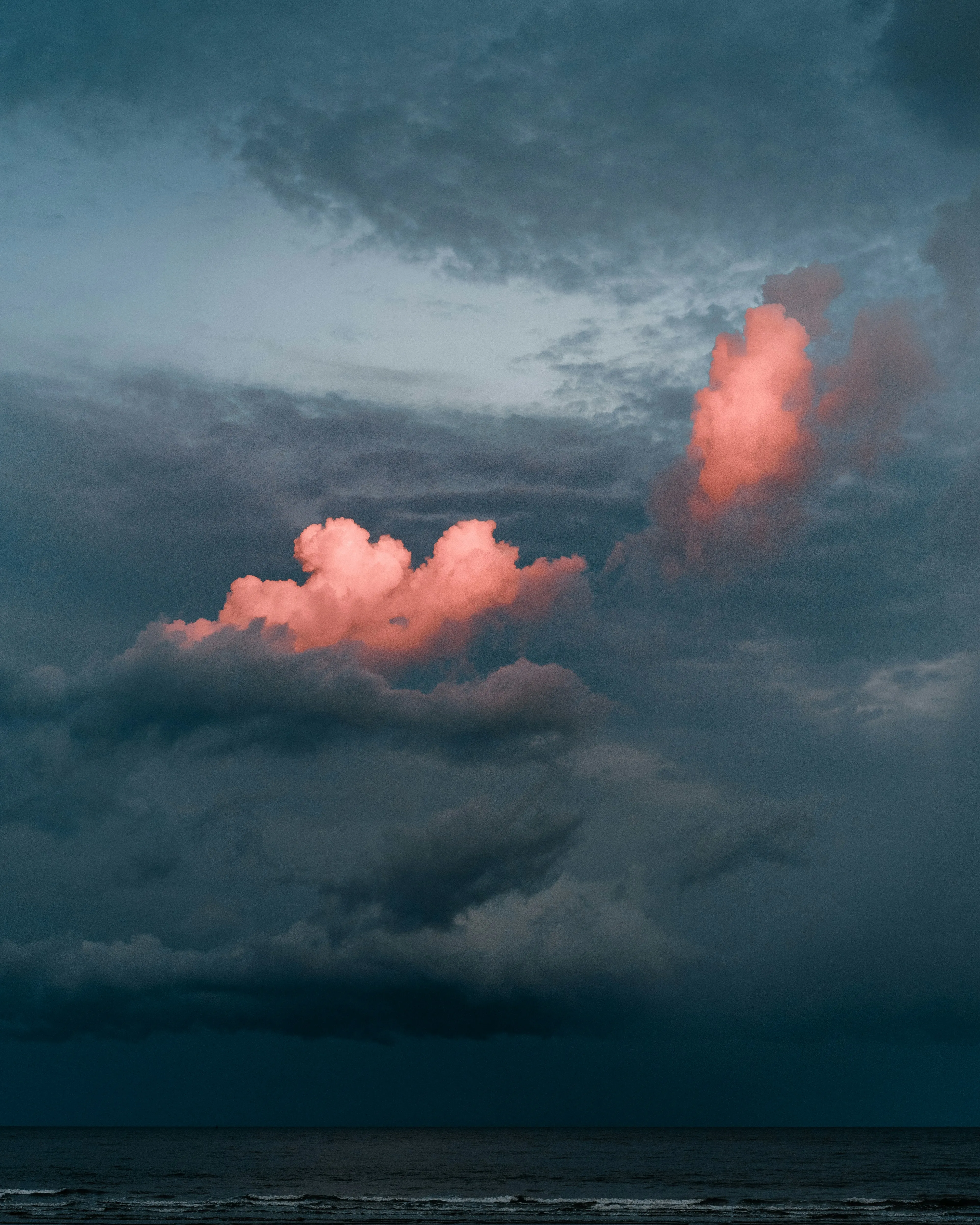 Dark Sky with Glowing Pink Clouds Over the Ocean Wallpaper