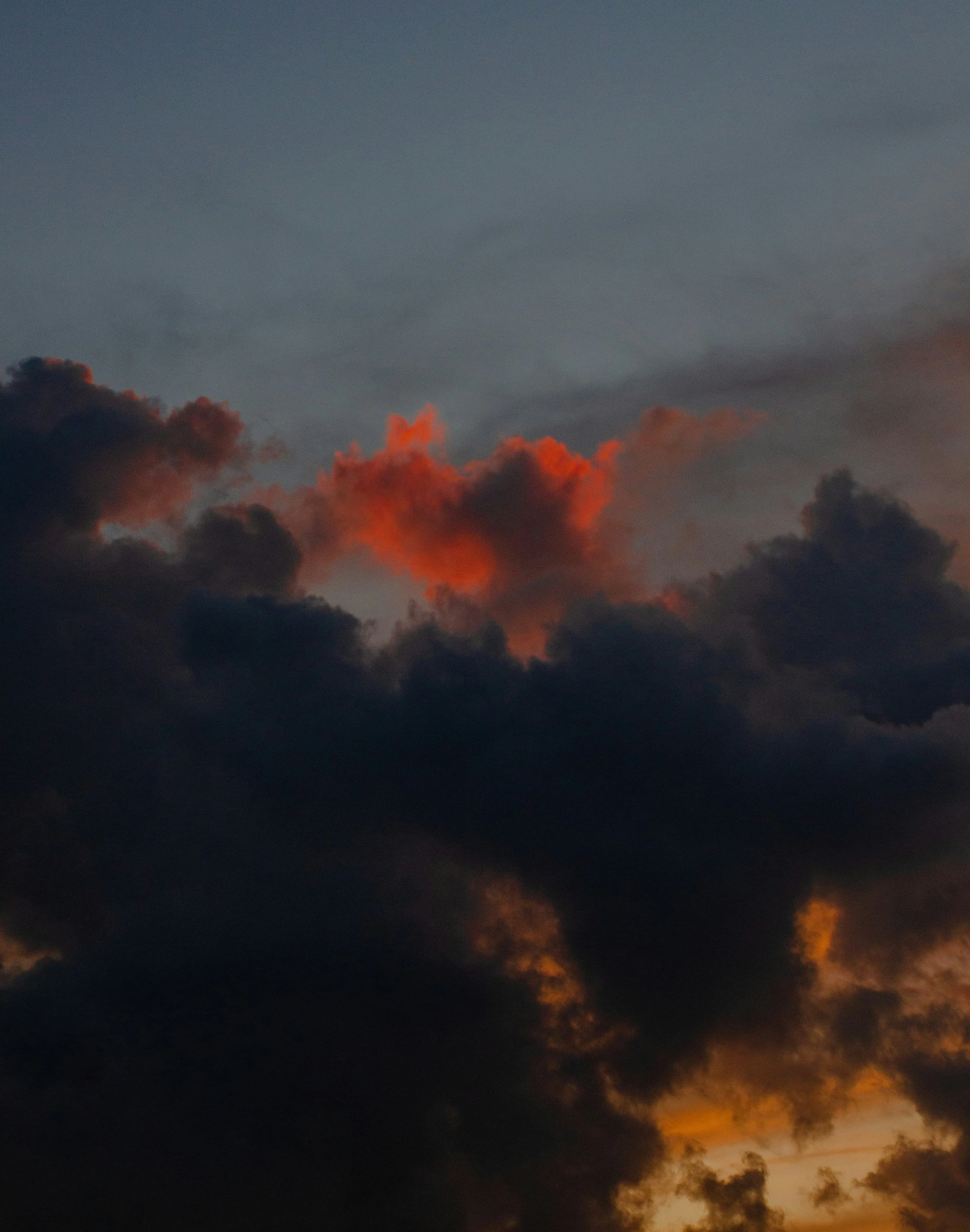 Dark Storm Clouds with Orange Sunset Glow Over Horizon