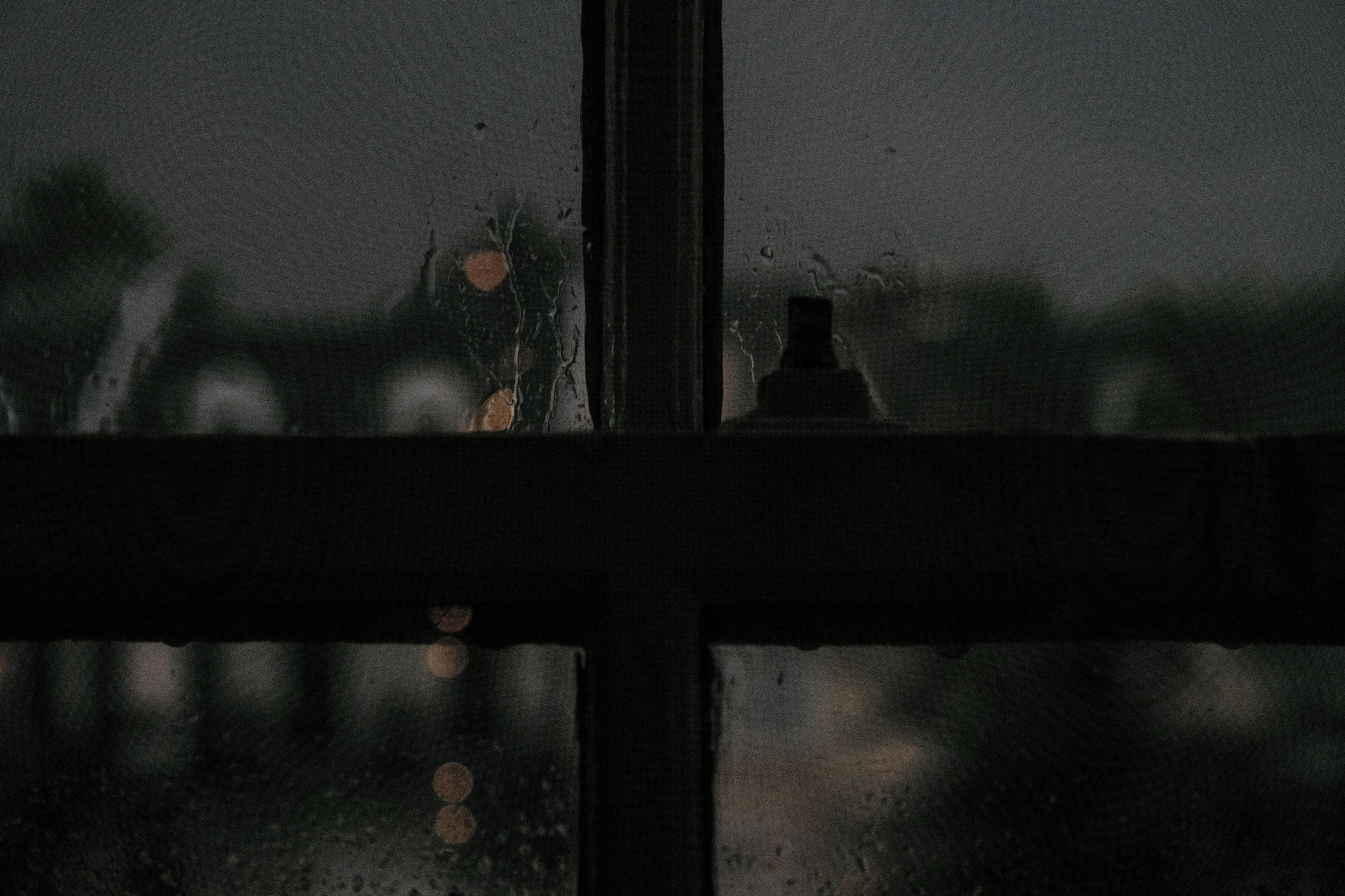 Darkened Room with Rain Droplets on Window Pane Wallpaper