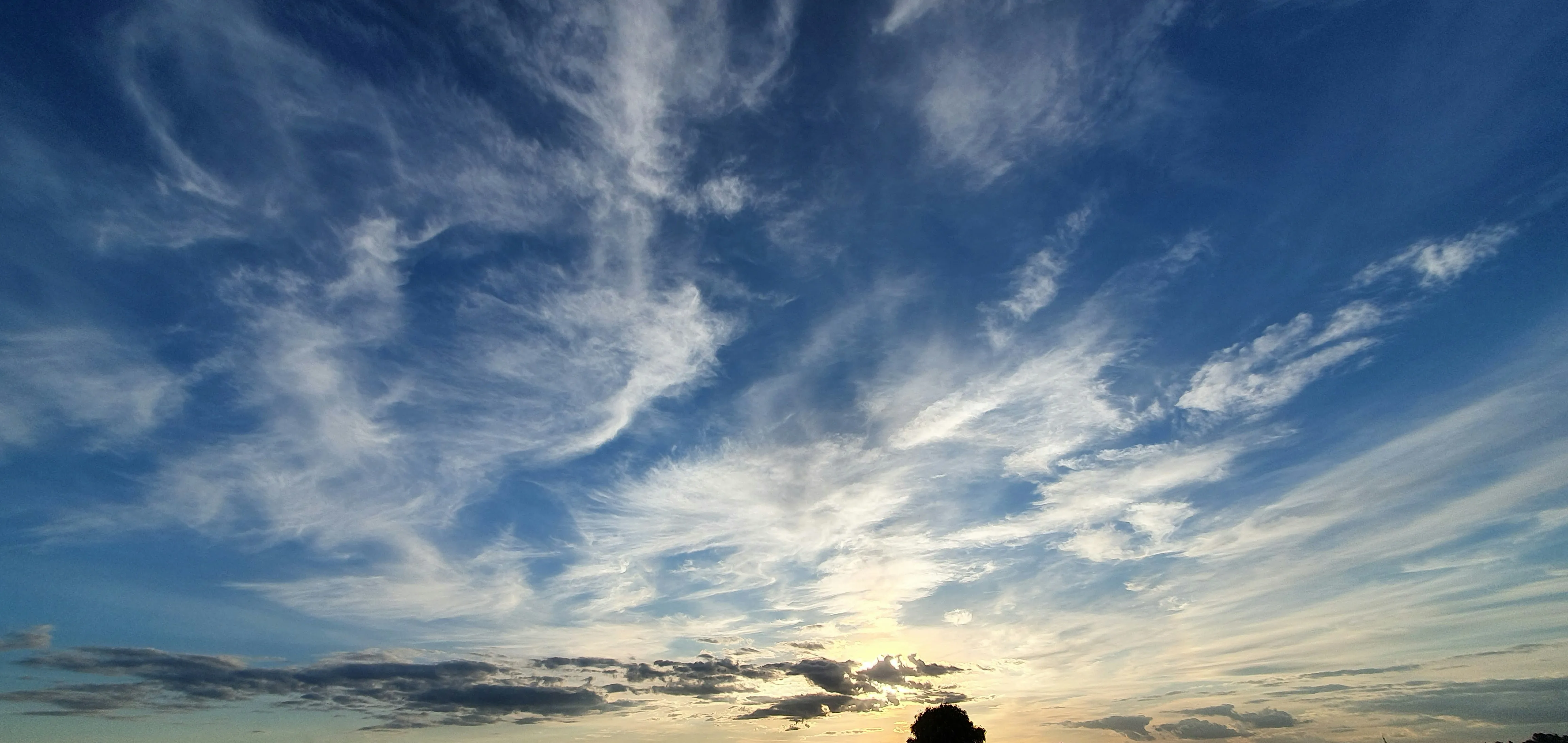 Dramatic Clouds Stretching Across Blue Sky Over Mountains