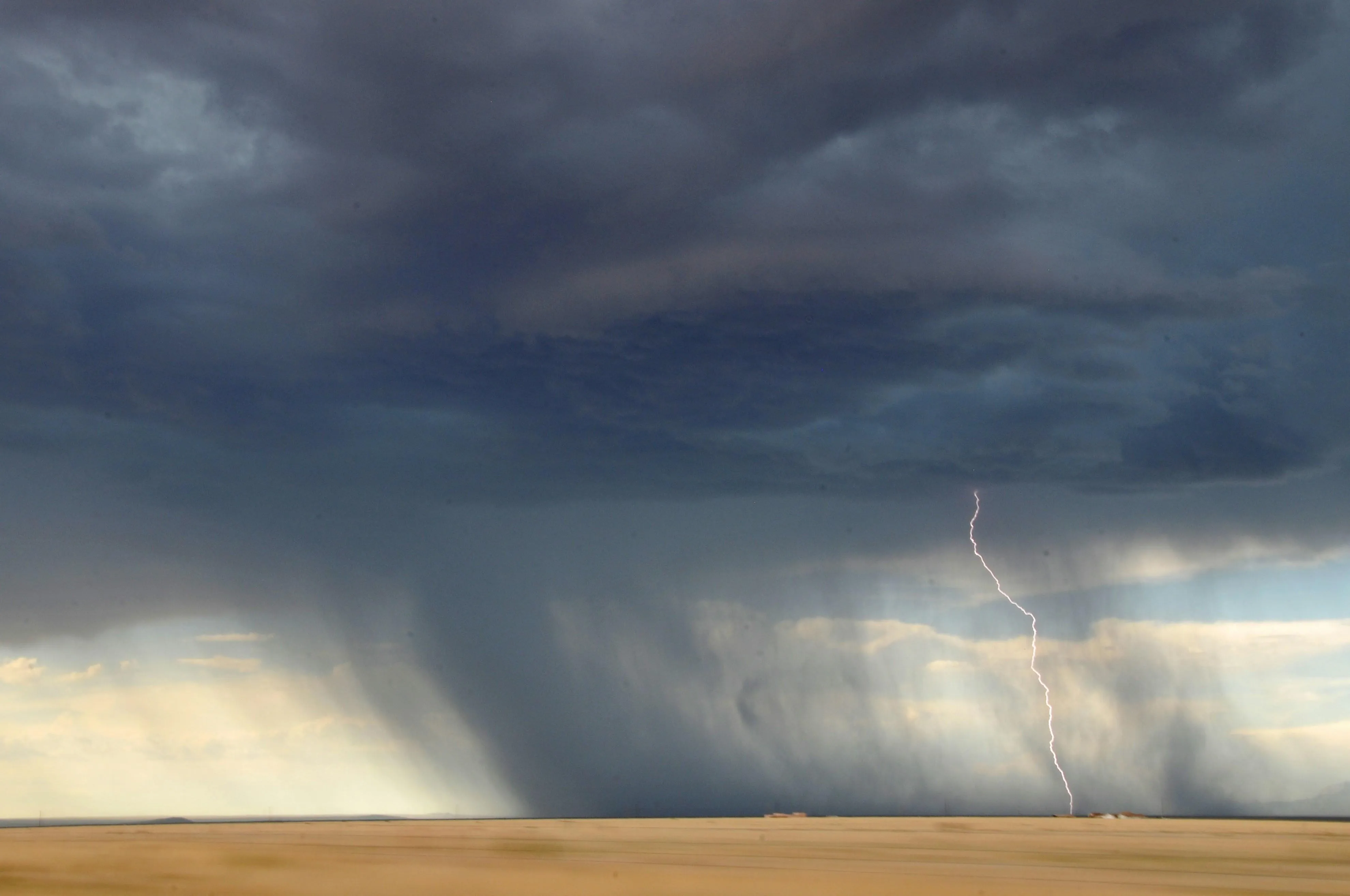 Dramatic Rainstorm Over Flat Landscape with Dark Clouds