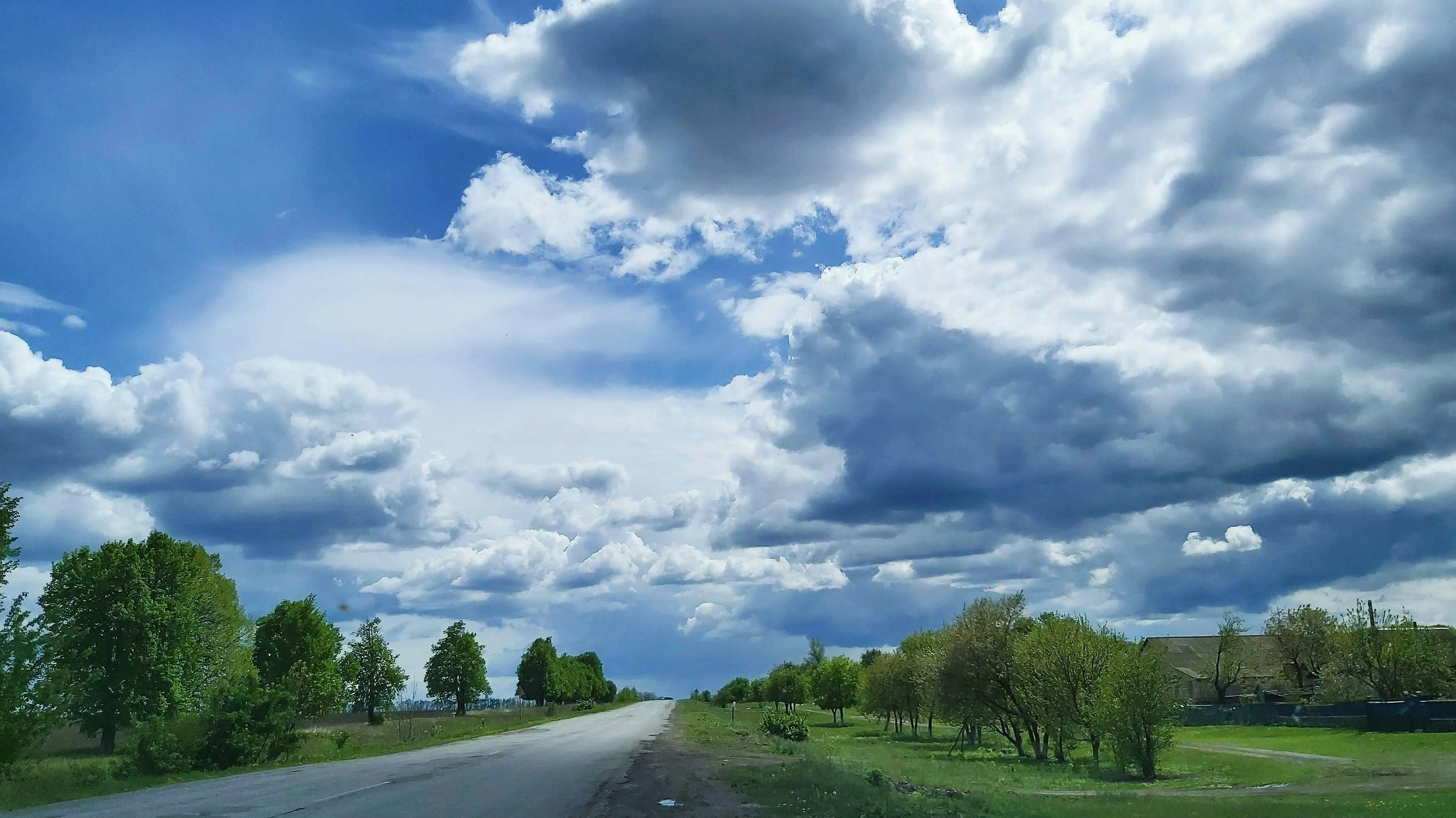 Expansive Green Field Under a Cloudy Blue Sky Image