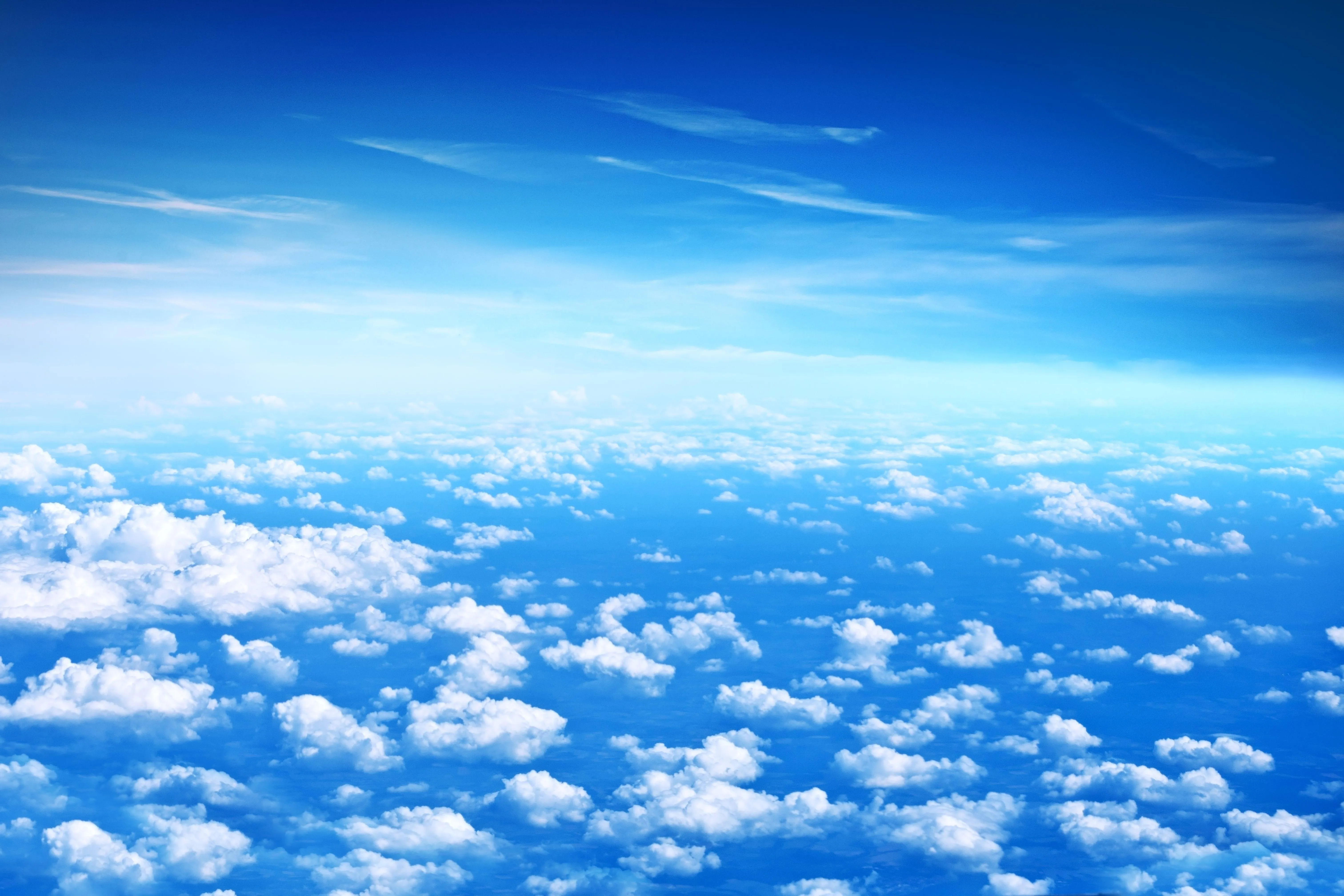 Expansive View of Fluffy White Clouds Under Bright Blue Sky