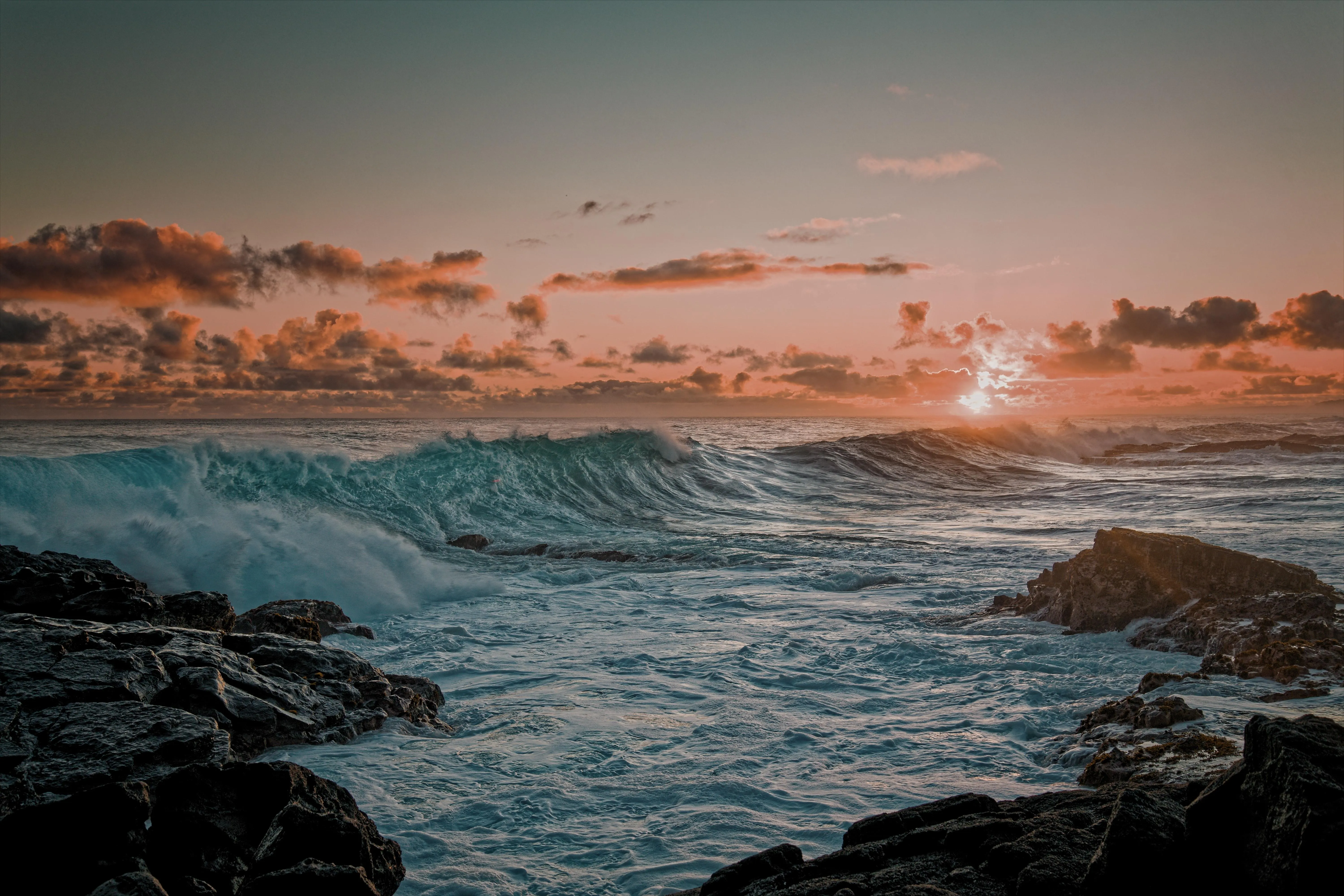Fiery coastal sunset with waves crashing ashore Wallpaper