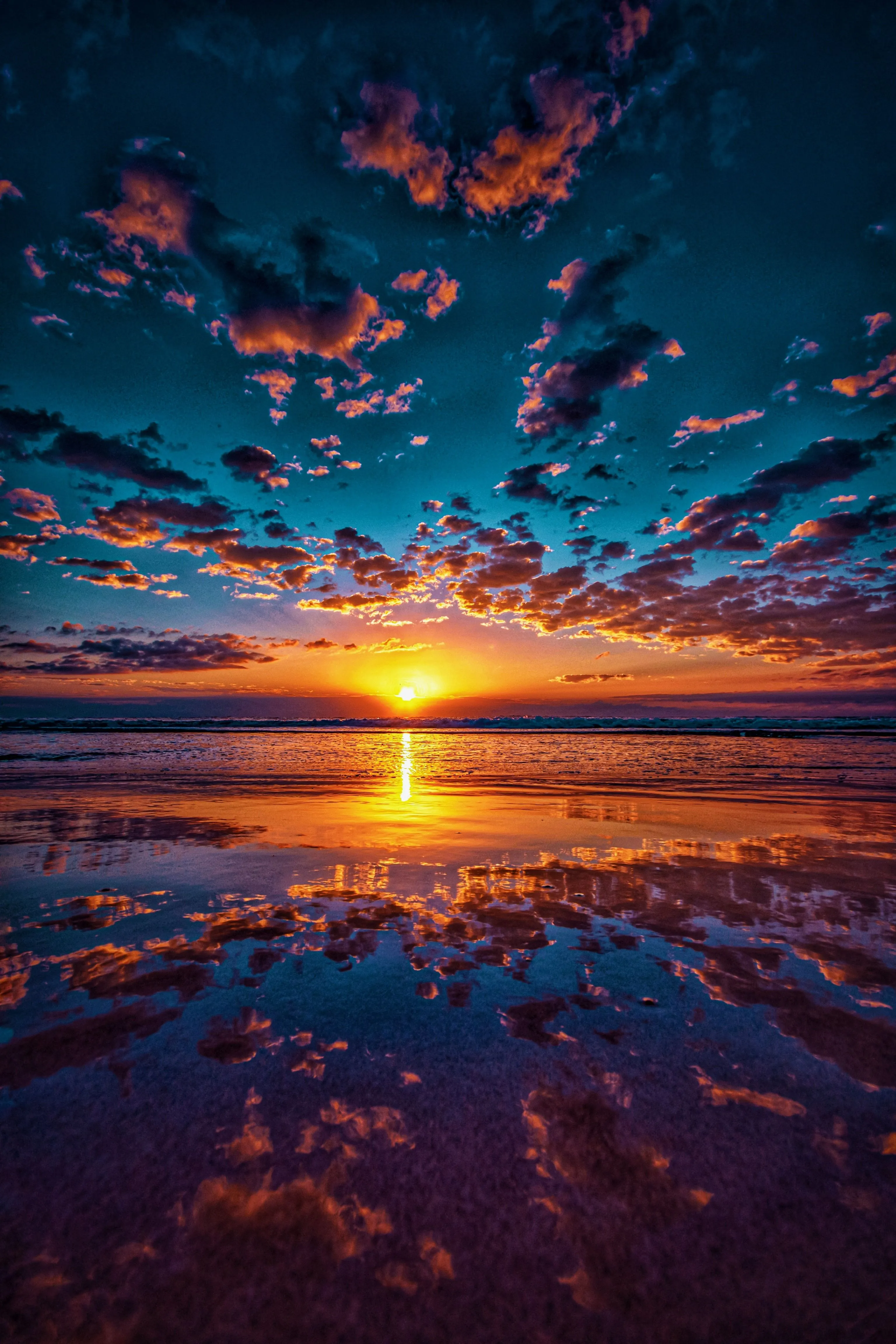 Fiery Sunset Sky Reflecting Over Ocean with Dramatic Clouds