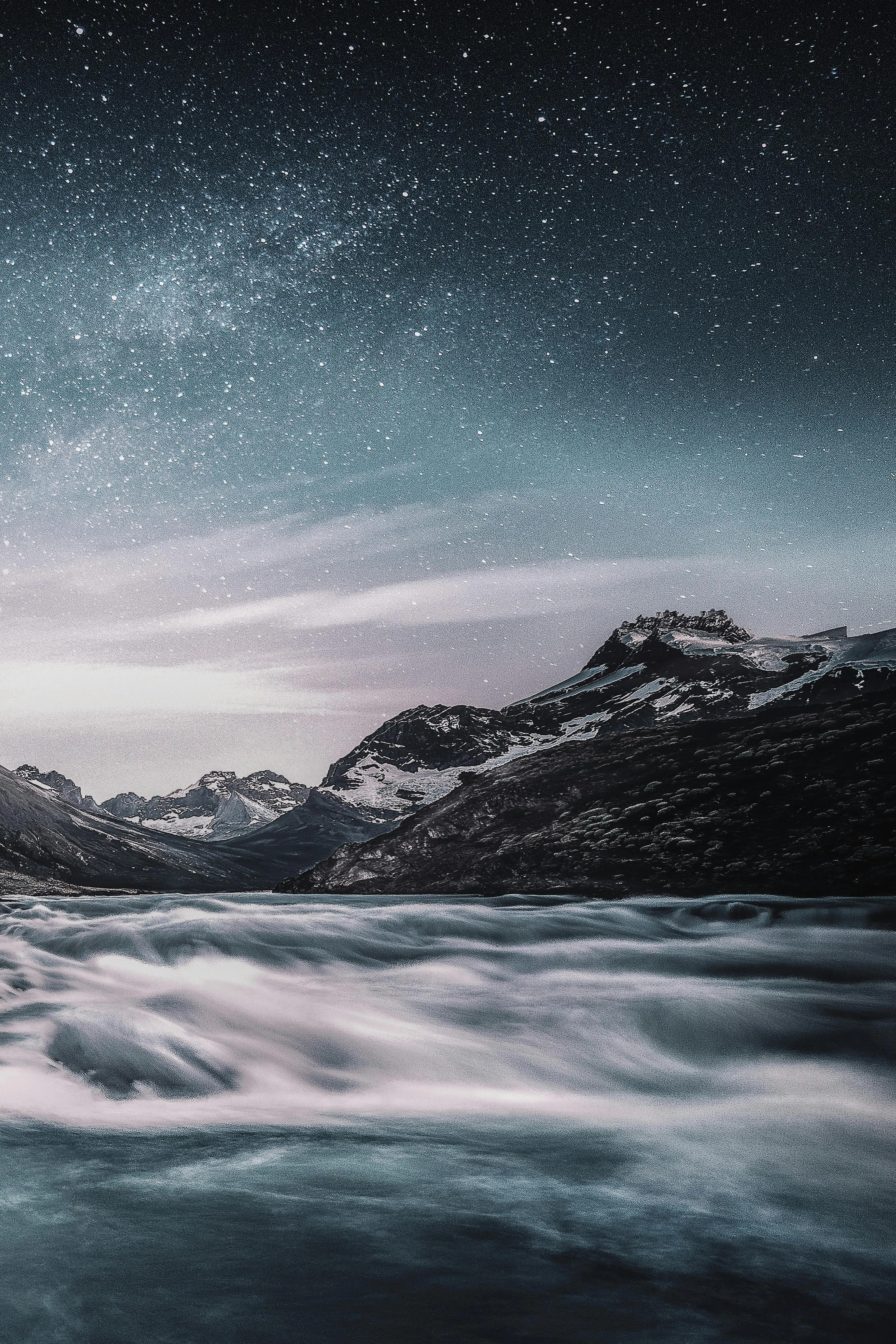 Flowing River with Mountain Backdrop Under Starry Night Sky