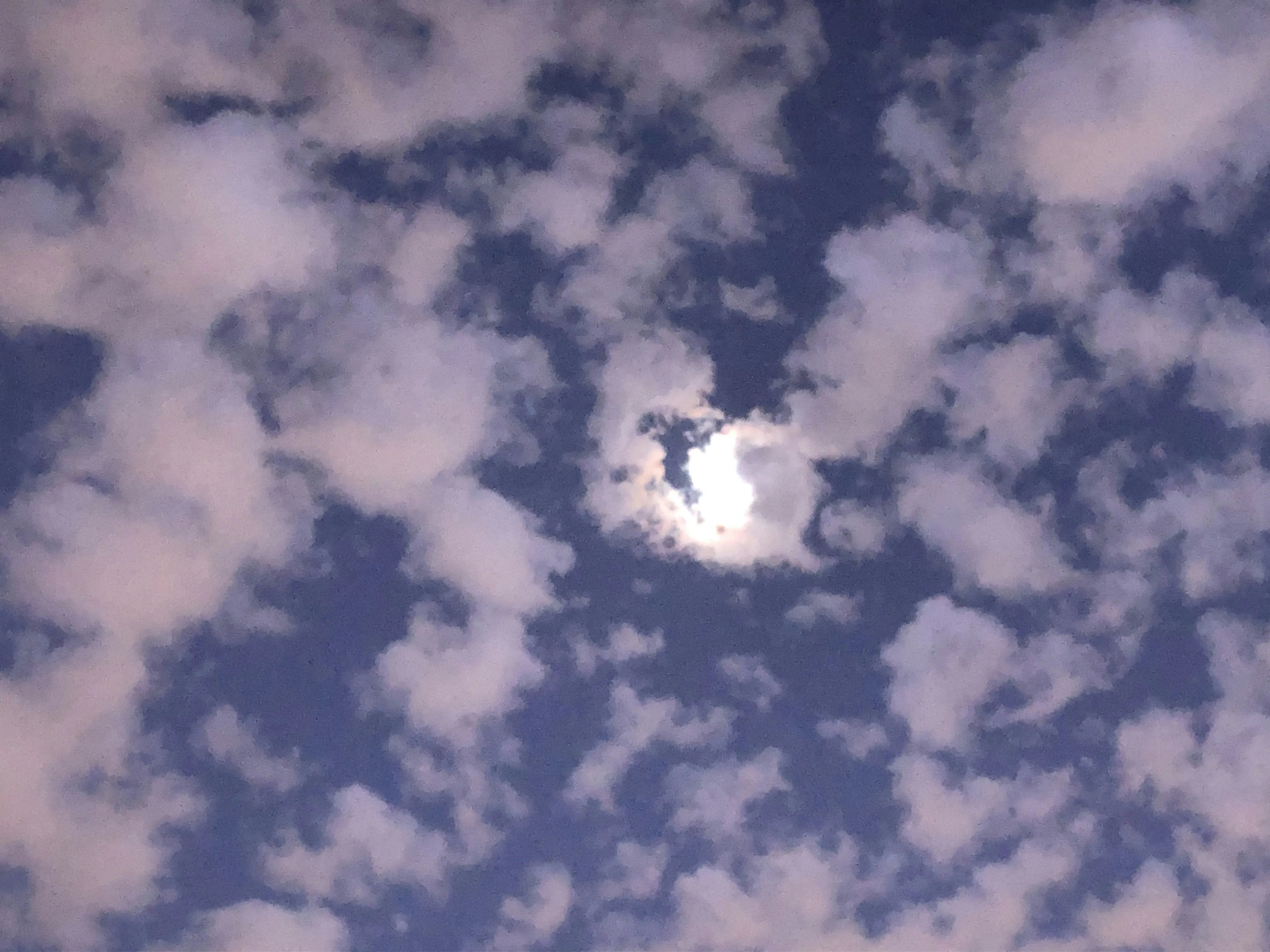 Fluffy Clouds with Sun Peeking Through Bright Sky