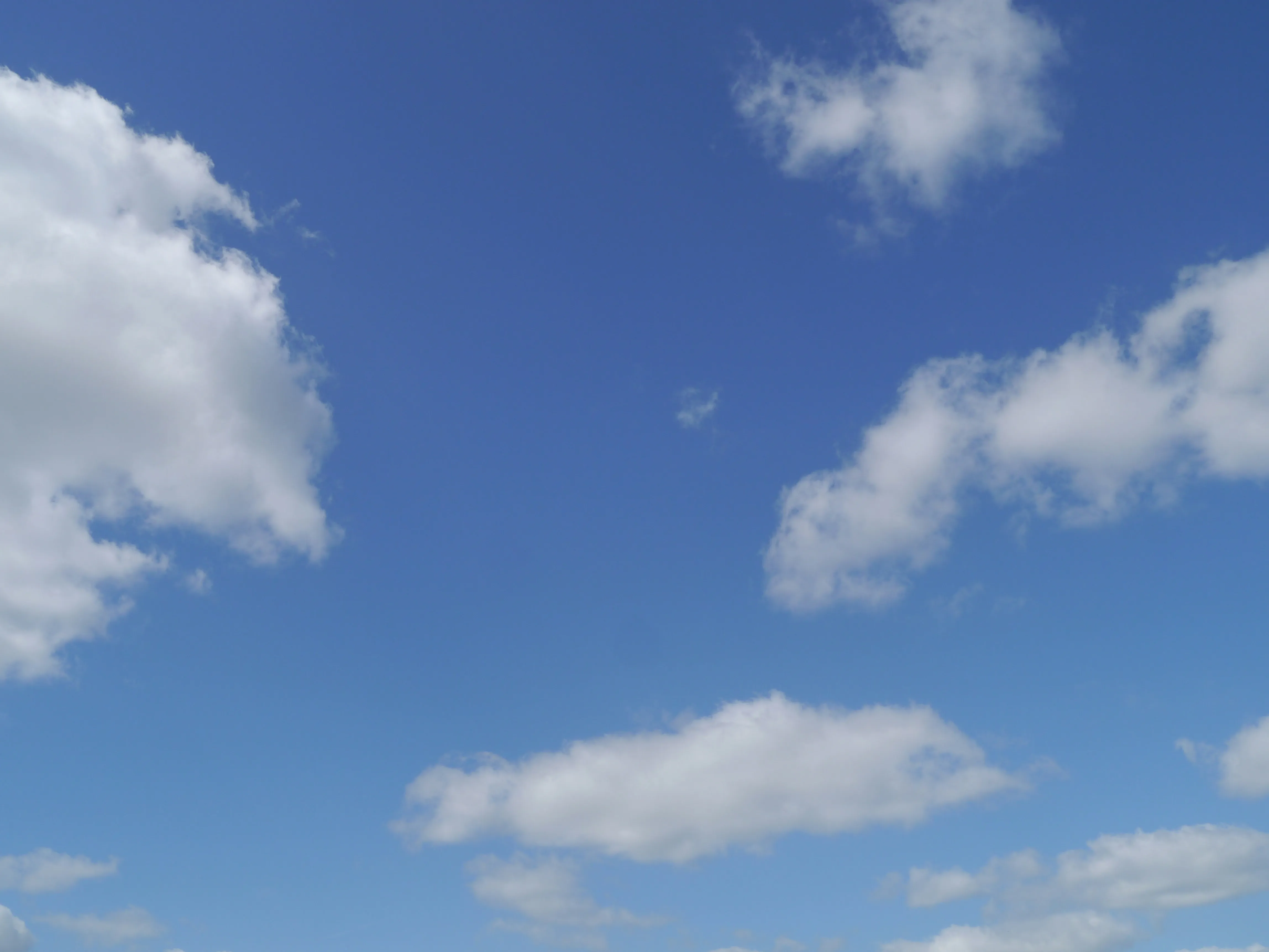 Fluffy White Clouds Floating Across Bright Blue Sky