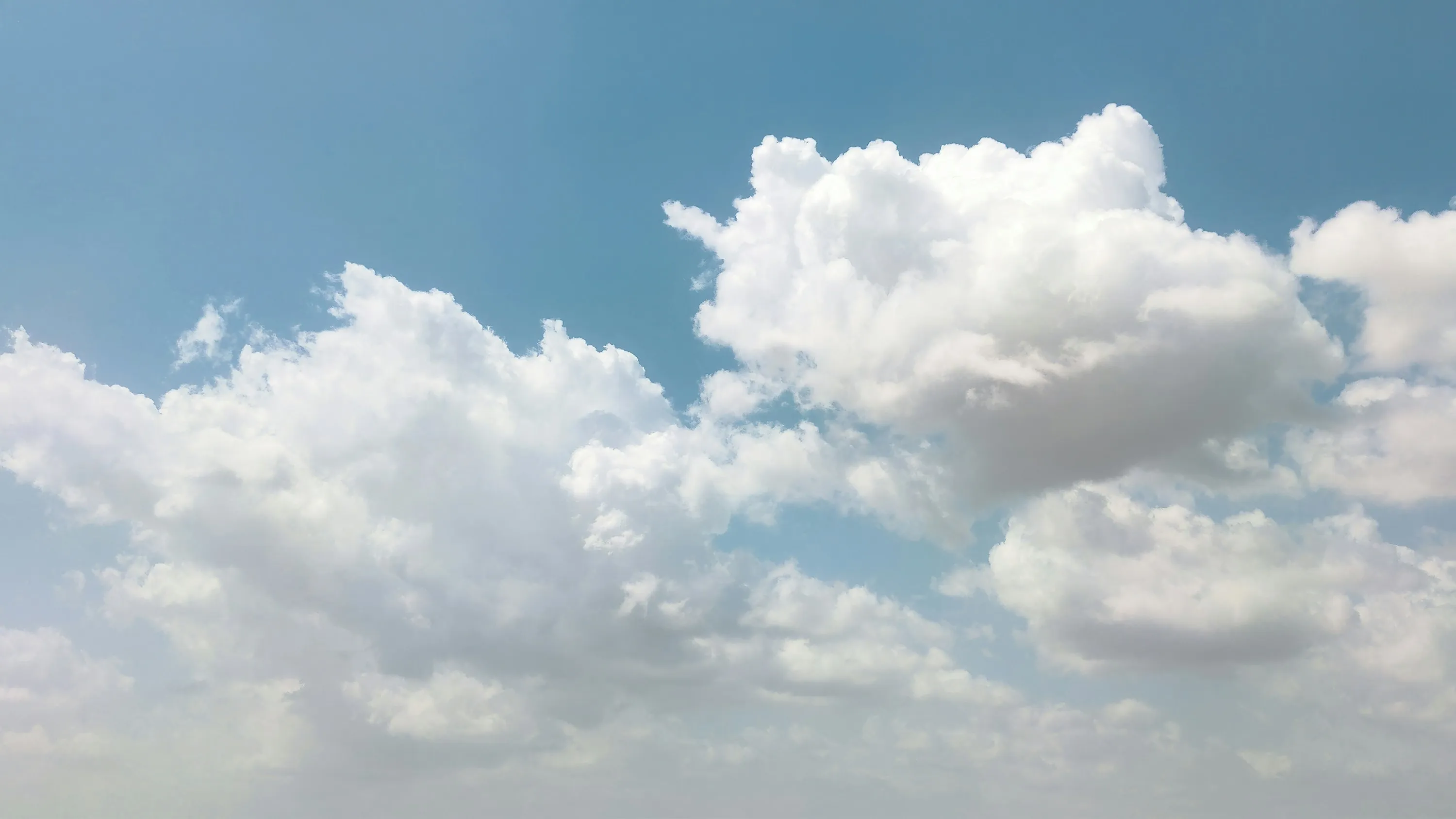 Fluffy White Clouds Scatter Across Bright Blue Sky Wallpaper