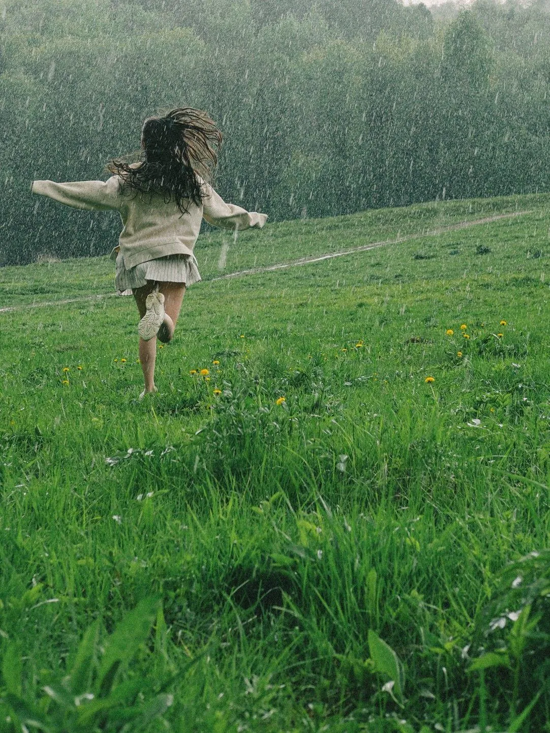Girl Running Barefoot in Rainy Field with Arms Open
