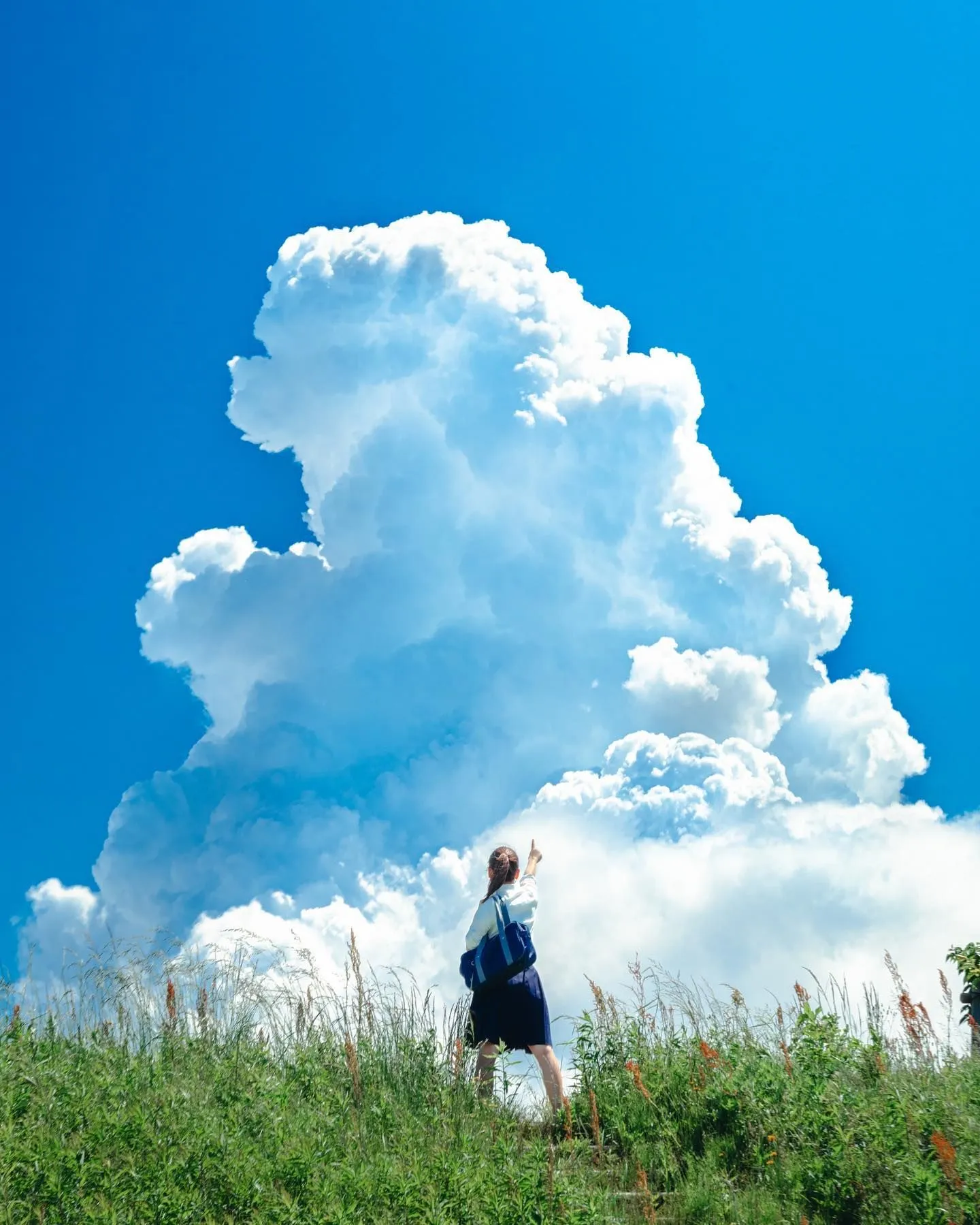 Girl Standing Under Towering White Clouds on a Sunny Day