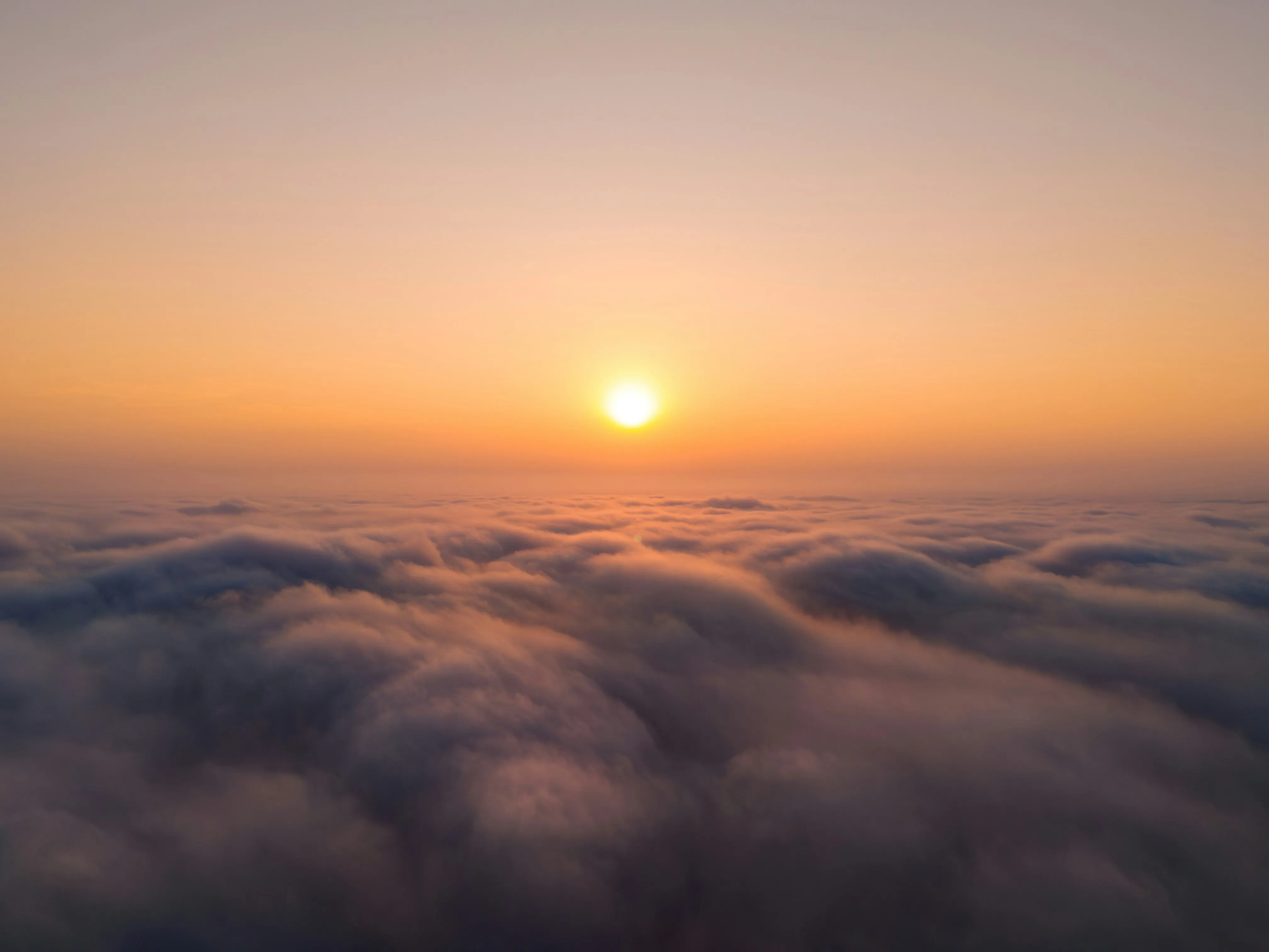 Golden Sunrise Over Misty Landscape Covered in Low Clouds