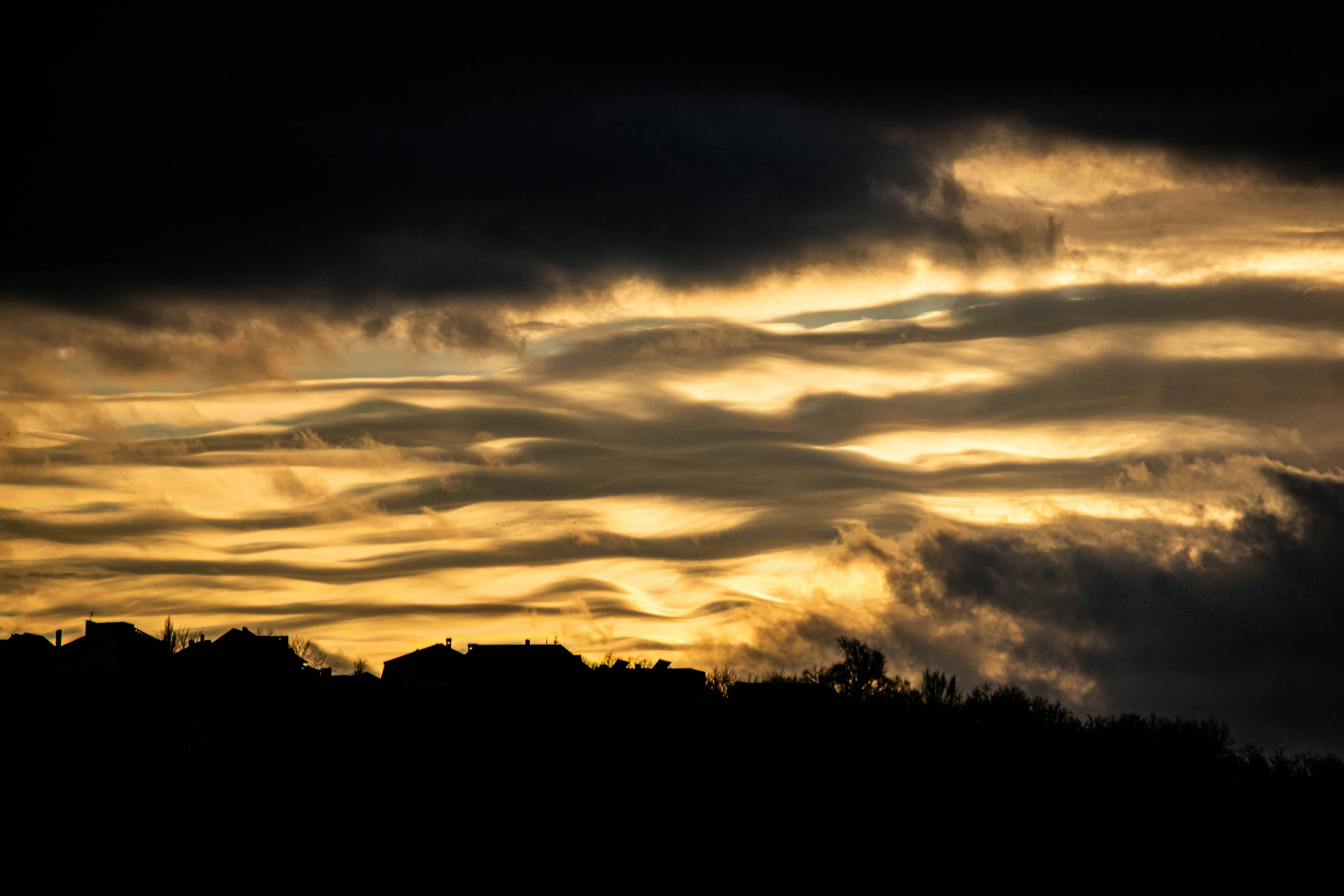 Golden Sunset Clouds Over Silhouetted Landscape Wallpaper