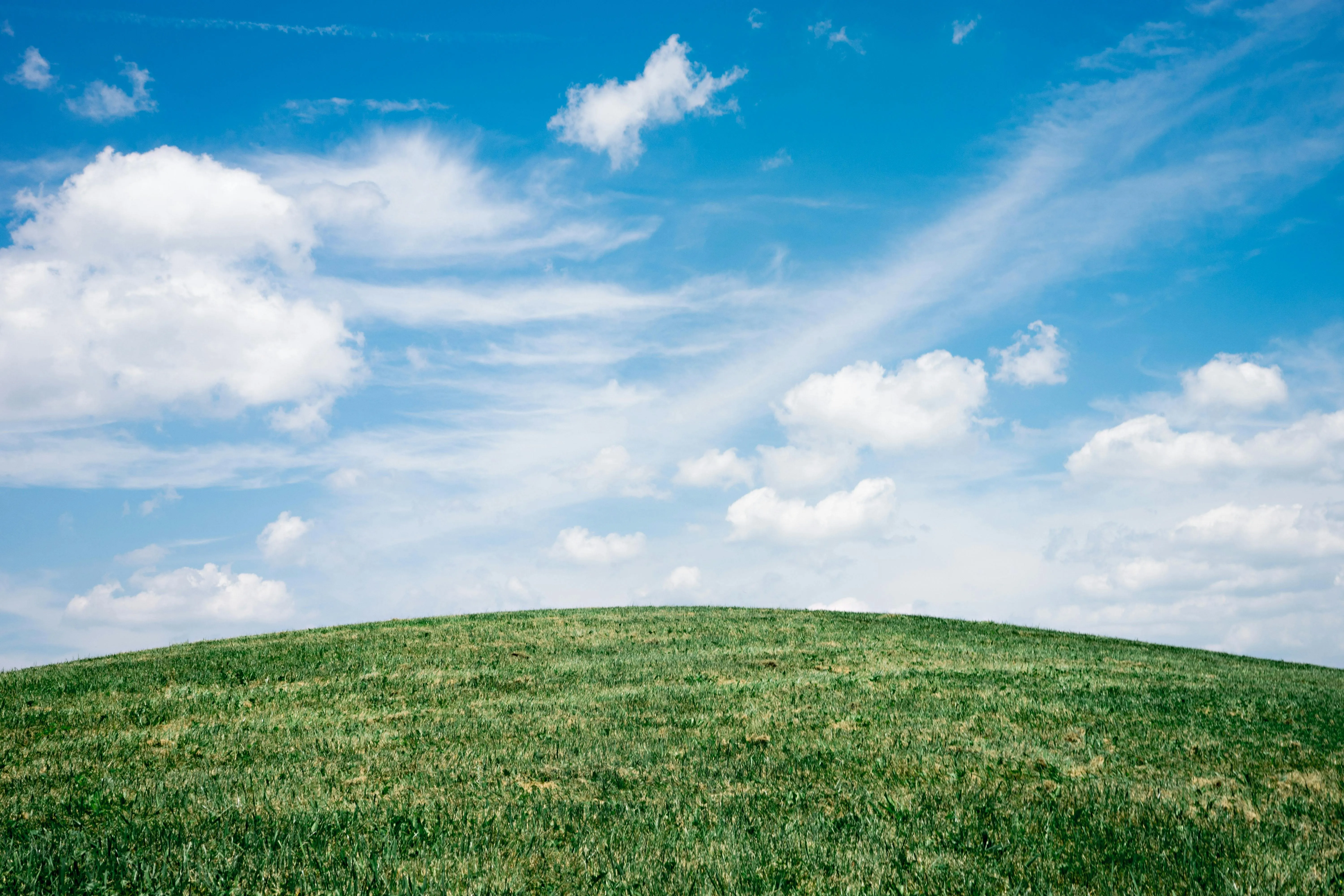 Green Hills Under a Blue Sky with Puffy Clouds Wallpaper