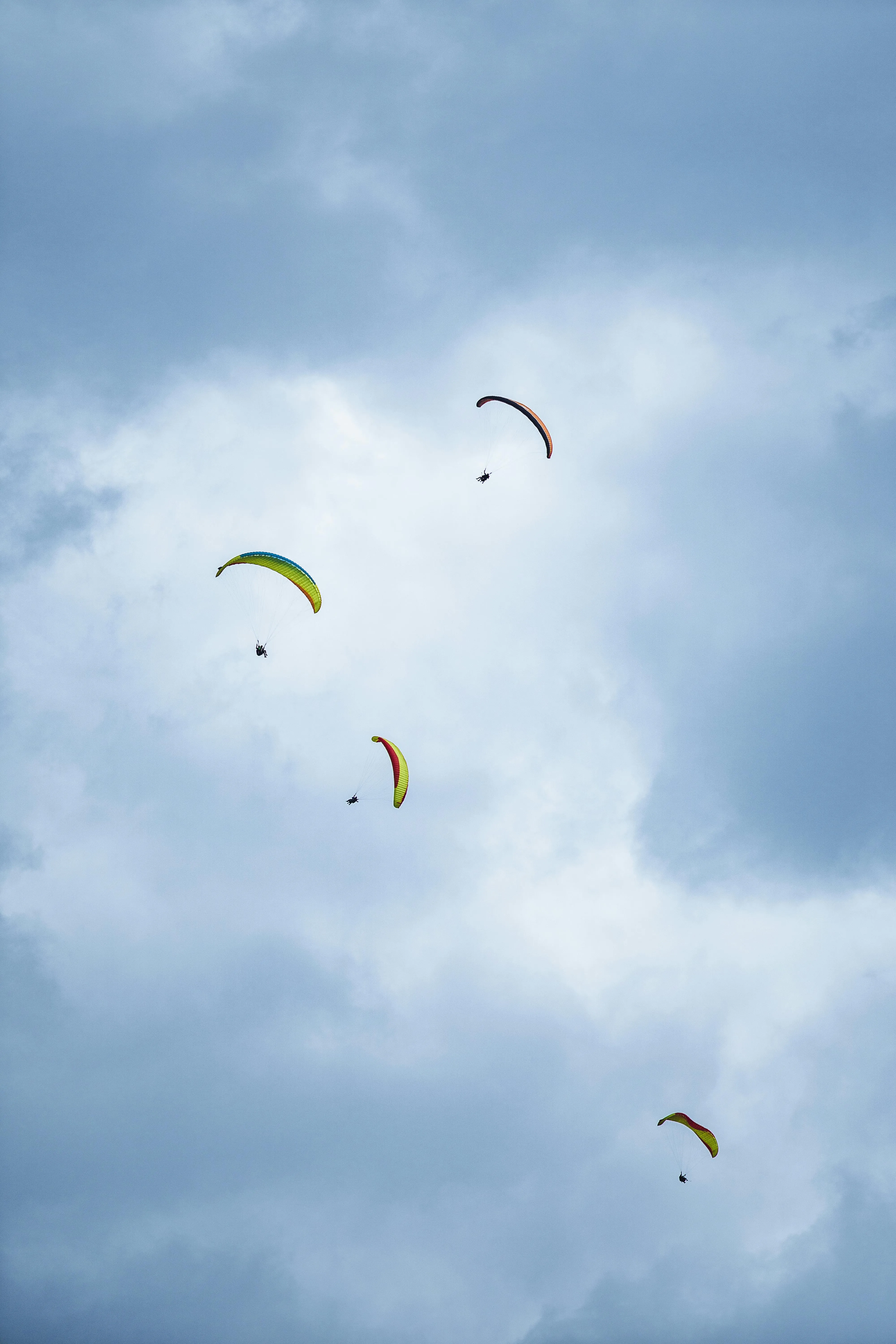 Group of Paragliders Flying Under a Bright Cloudy Sky