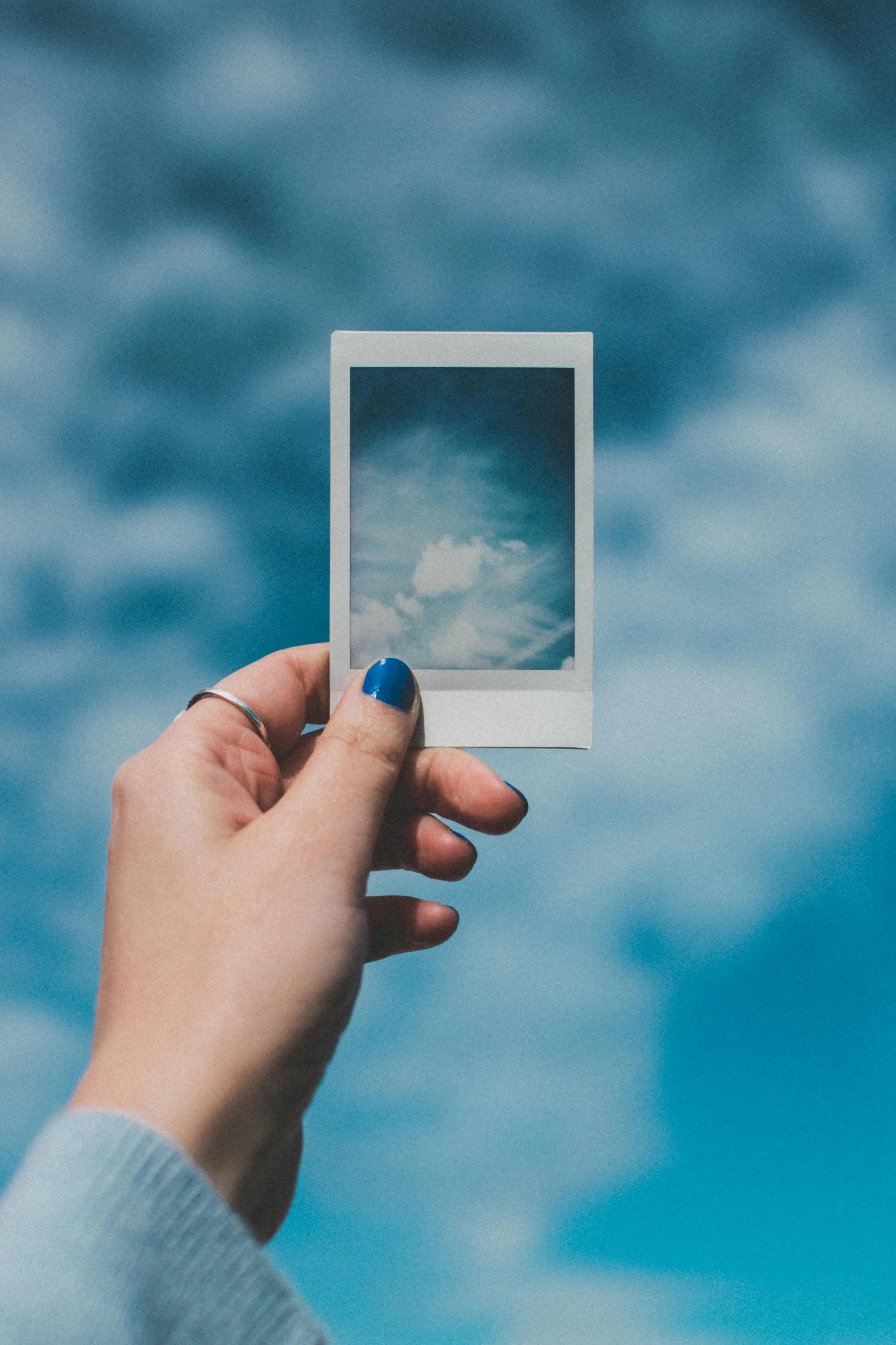 Hand Holding Frame To Capture Clouds in the Bright Blue Sky