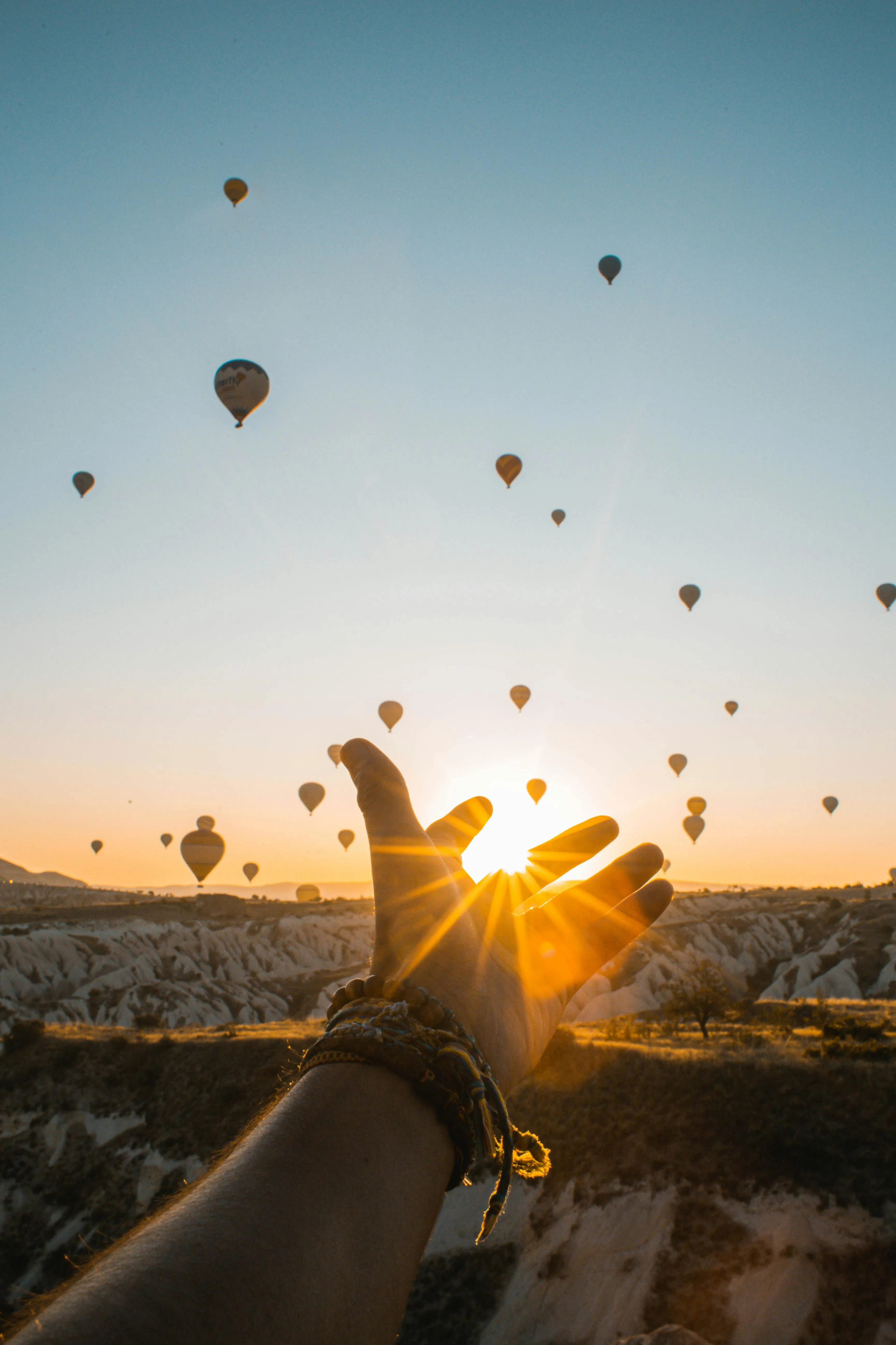 Hands Pointing Balloons Into a Cloudy Sunset Sky Image
