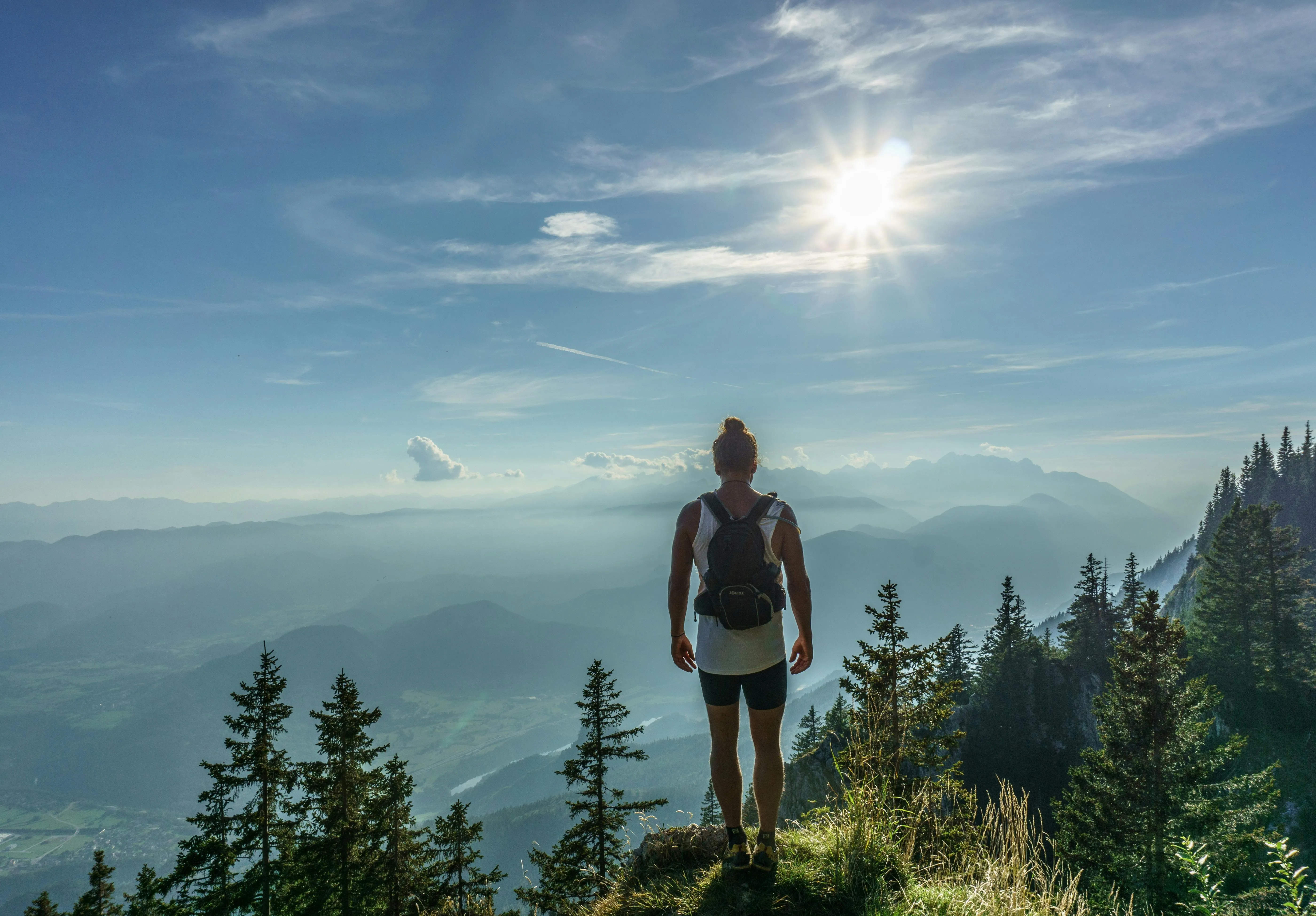 Hiker Standing on Mountain Edge with Bright Sun Wallpaper