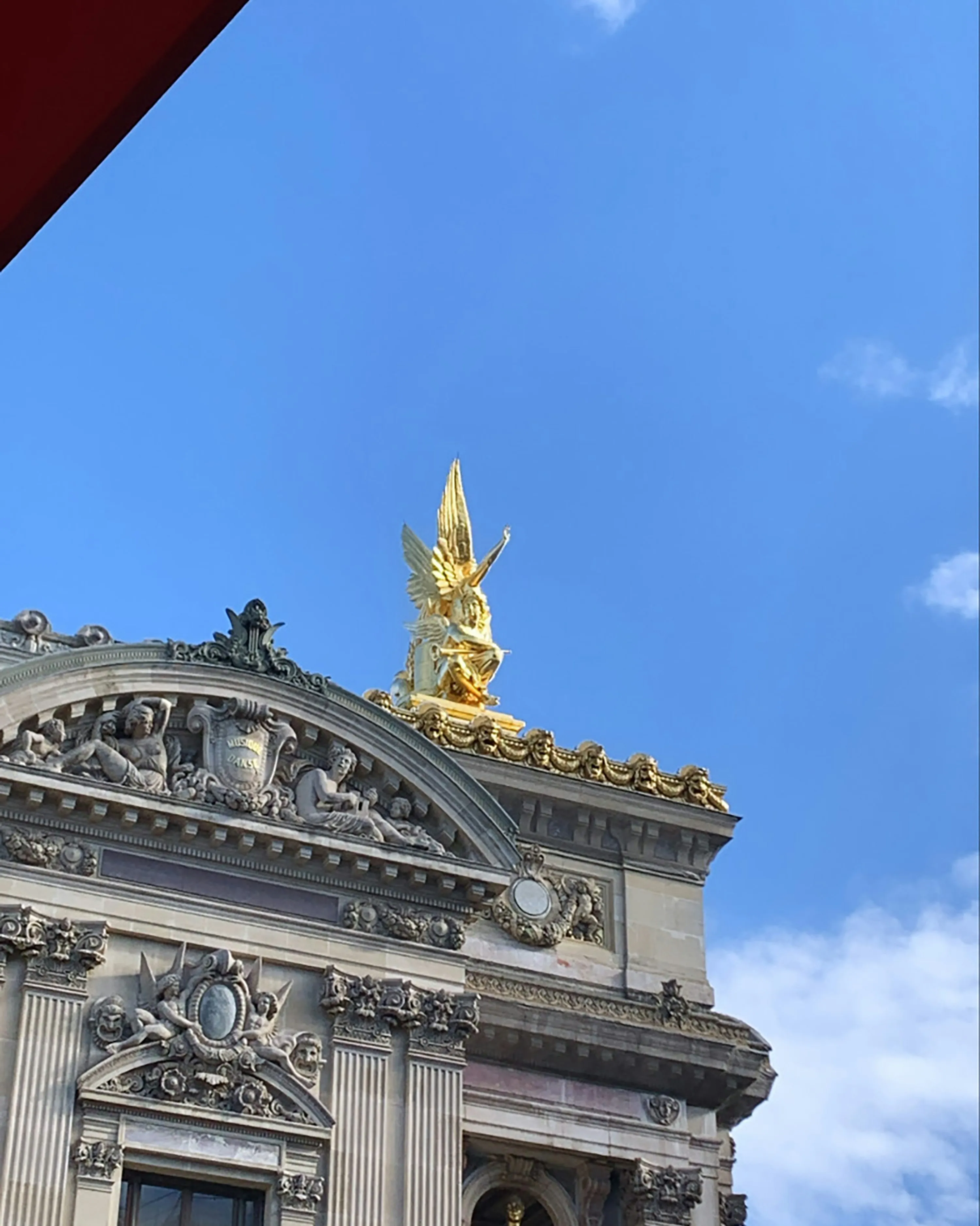 Historic Building with Golden Statue Against Blue Sky
