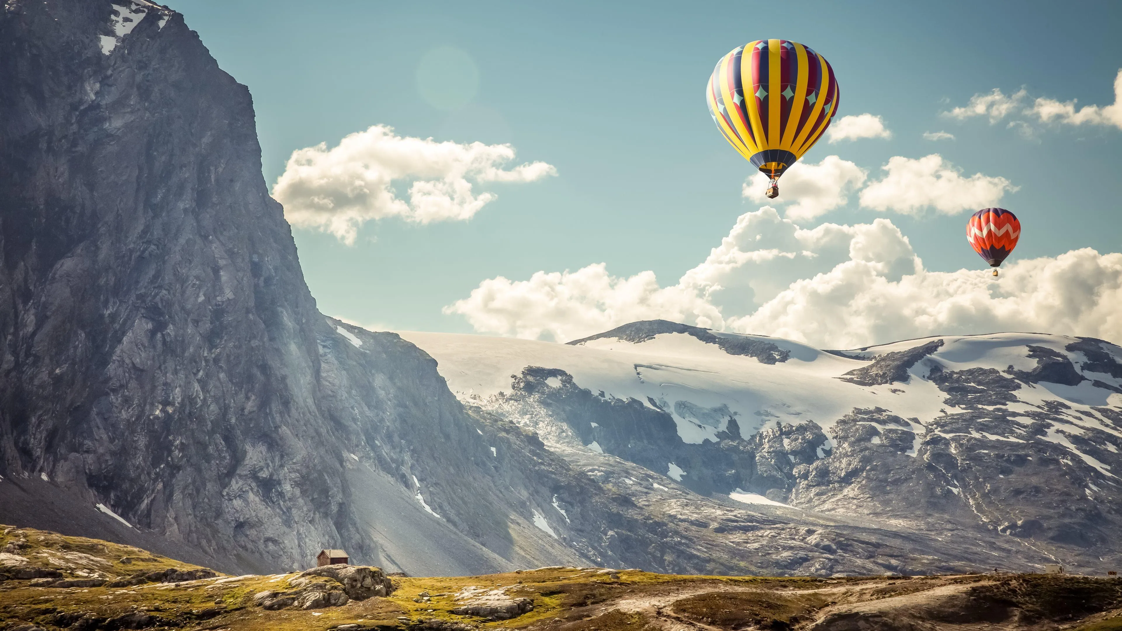 Hot air balloon drifting above rocky cliffs and clouds