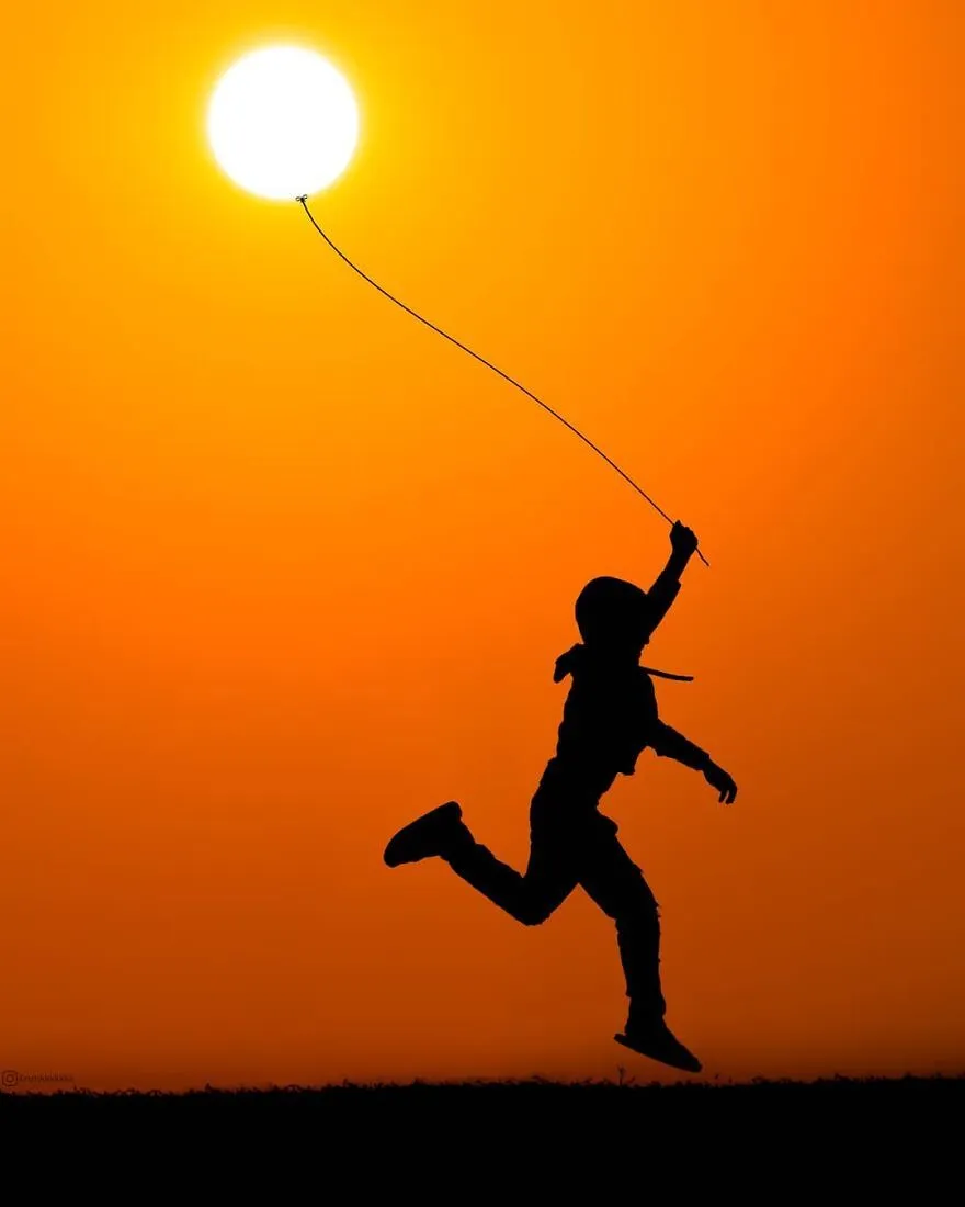 Joyful Child Holding Sun As Balloon in Golden Sunset Sky