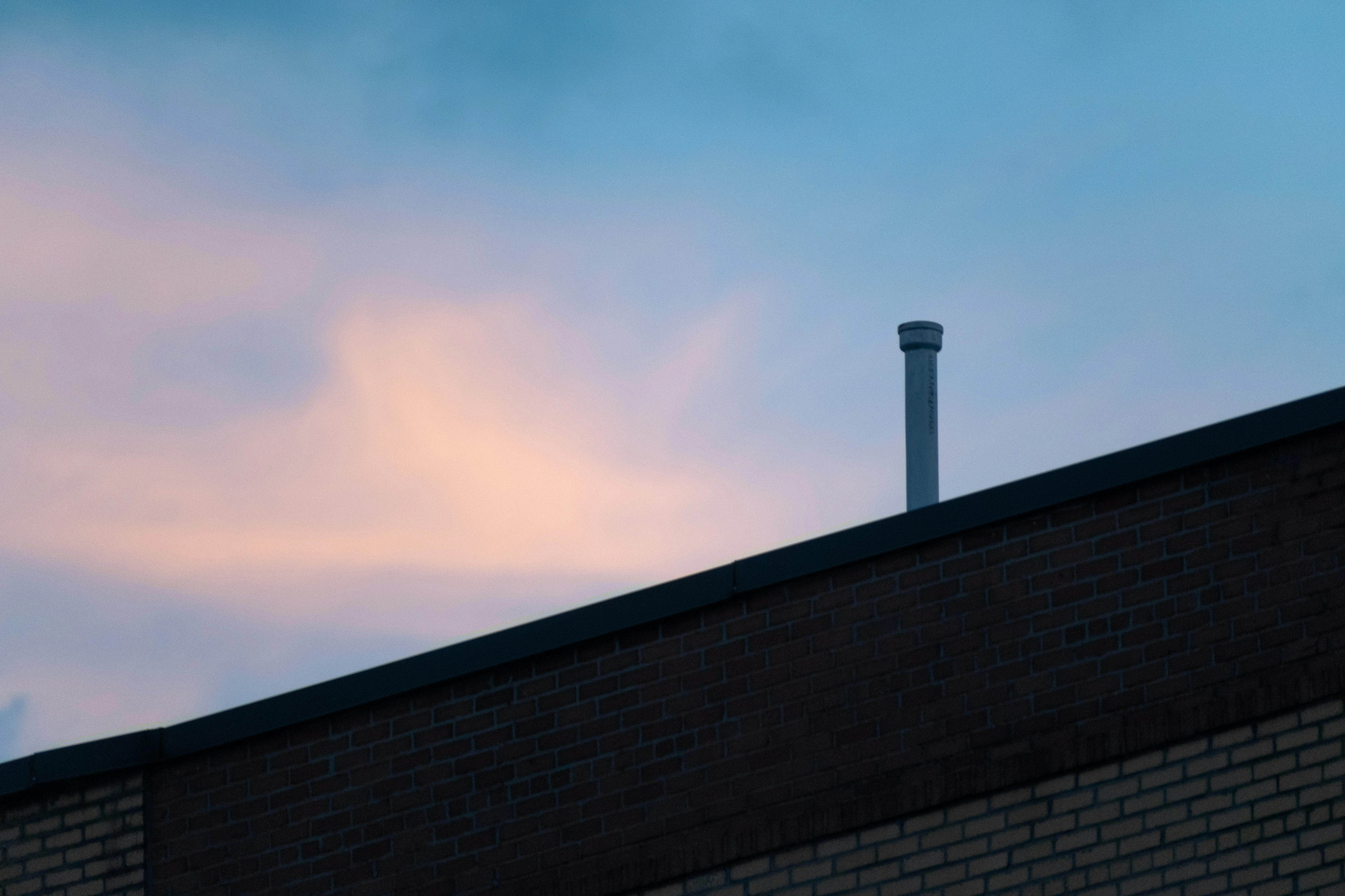 Light Pink Clouds Over Rooftop and Chimney Pipe Wallpaper