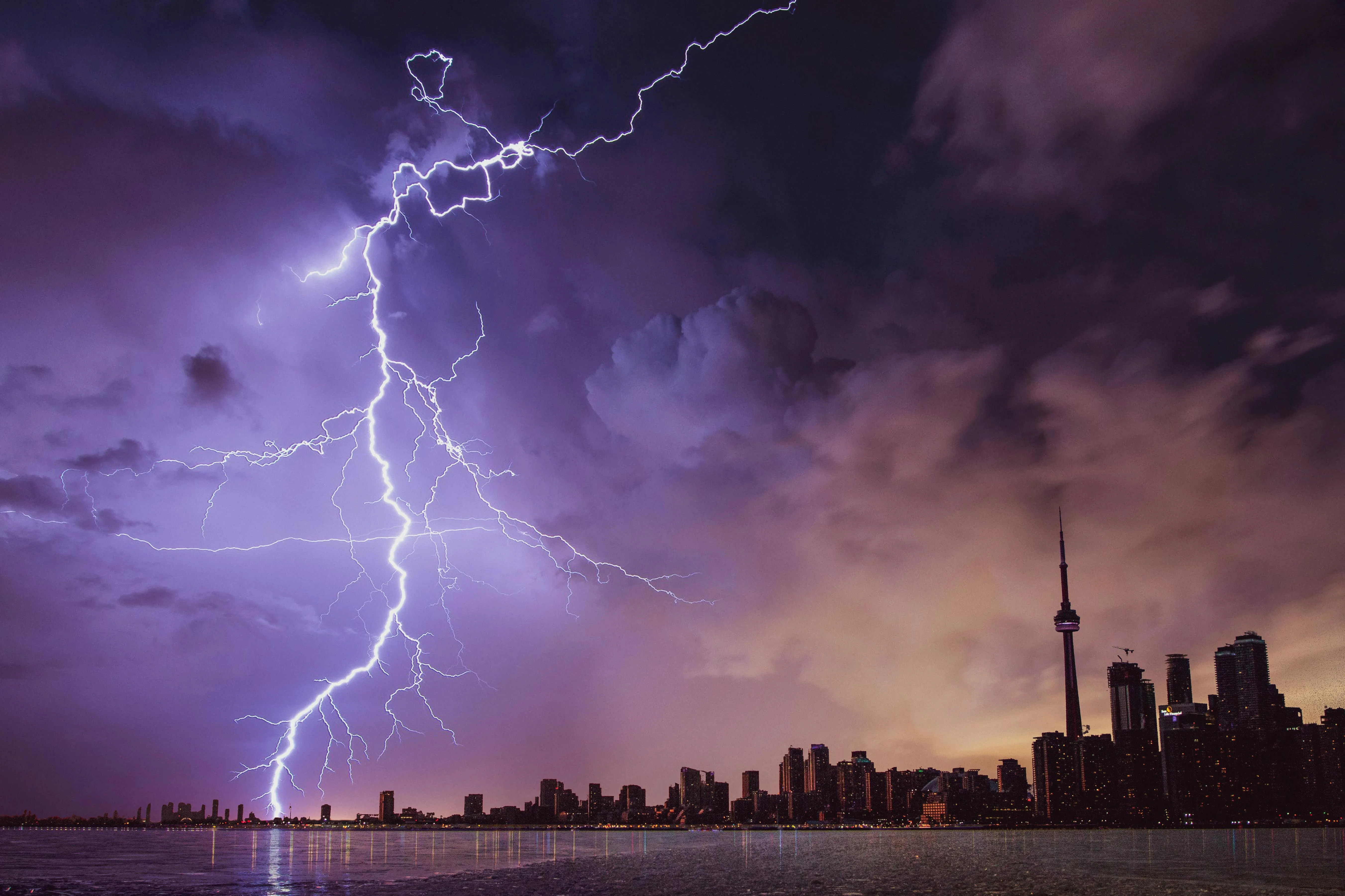 Lightning Striking City Under Deep Purple Storm Clouds