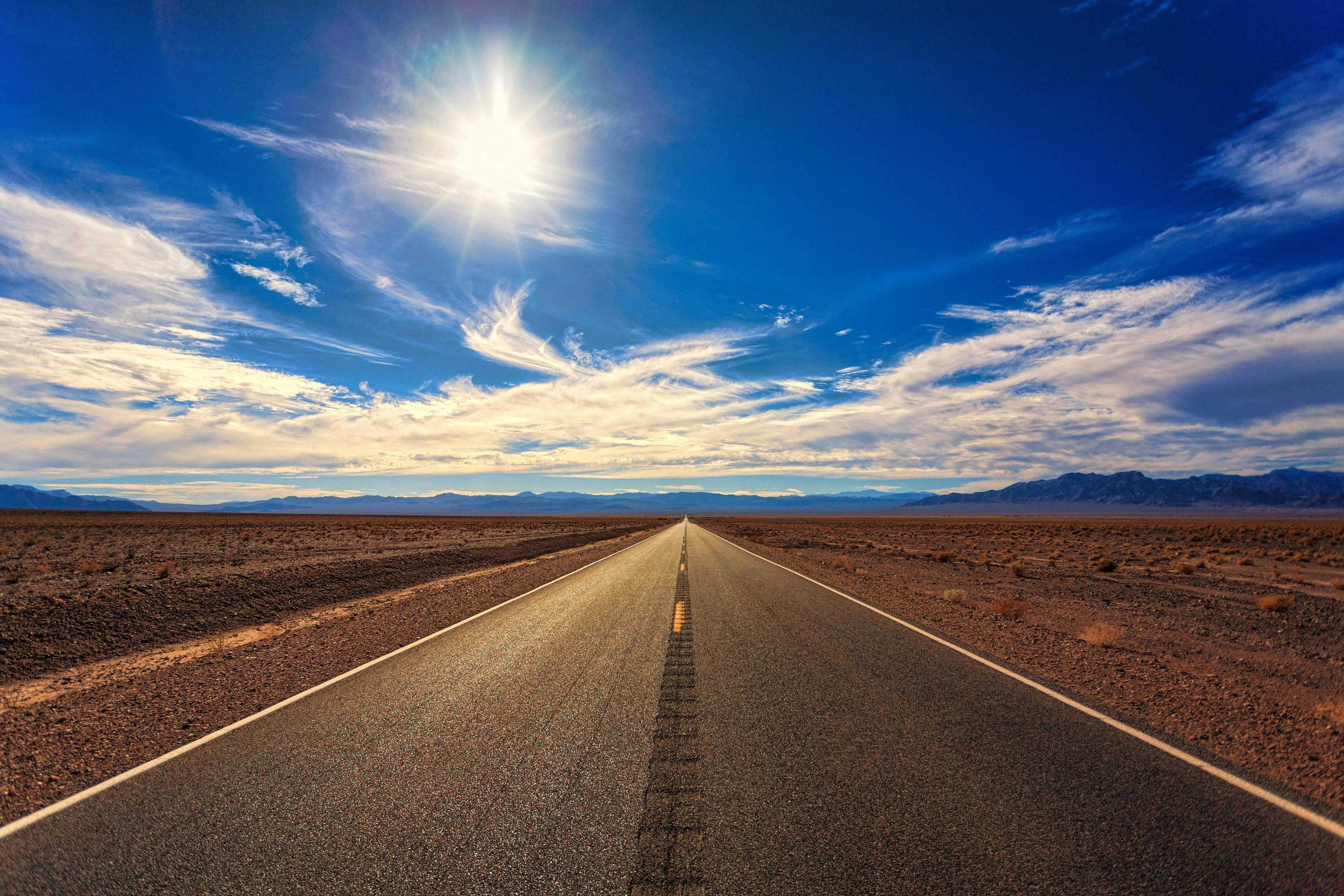 Long Road Stretching Under a Bright Sunny Sky Wallpaper