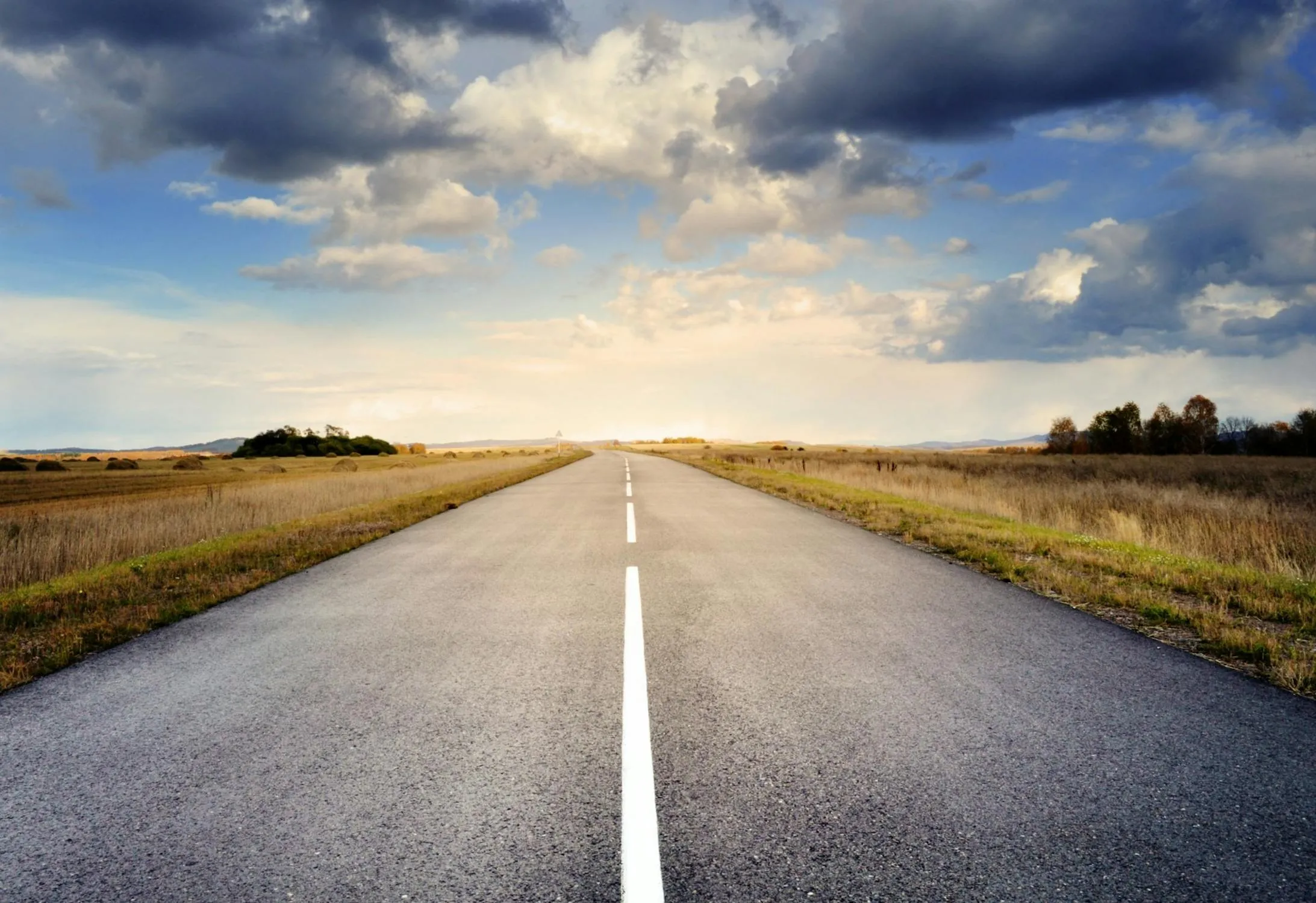 Long Road Through Farmland with Evening Sky and Clouds