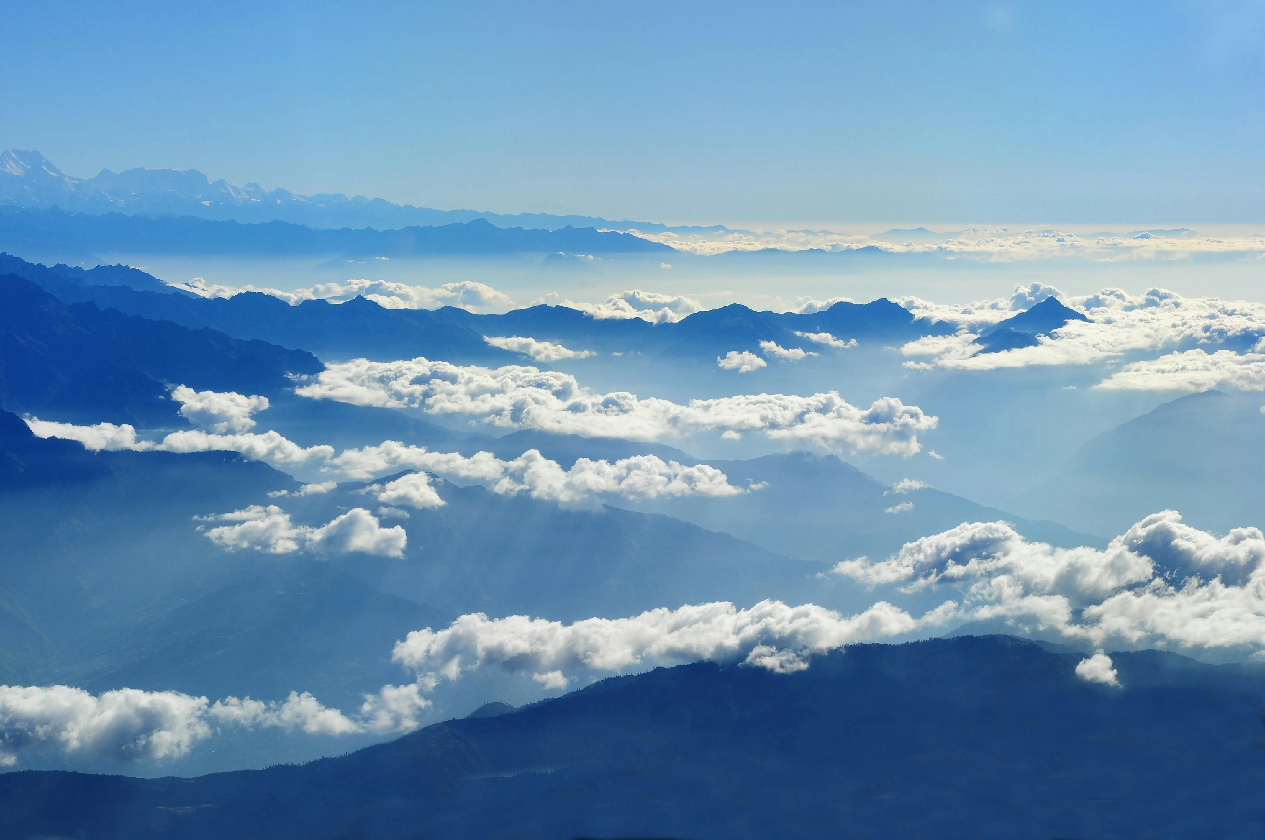 Majestic Mountain Peaks Covered By Soft White Clouds