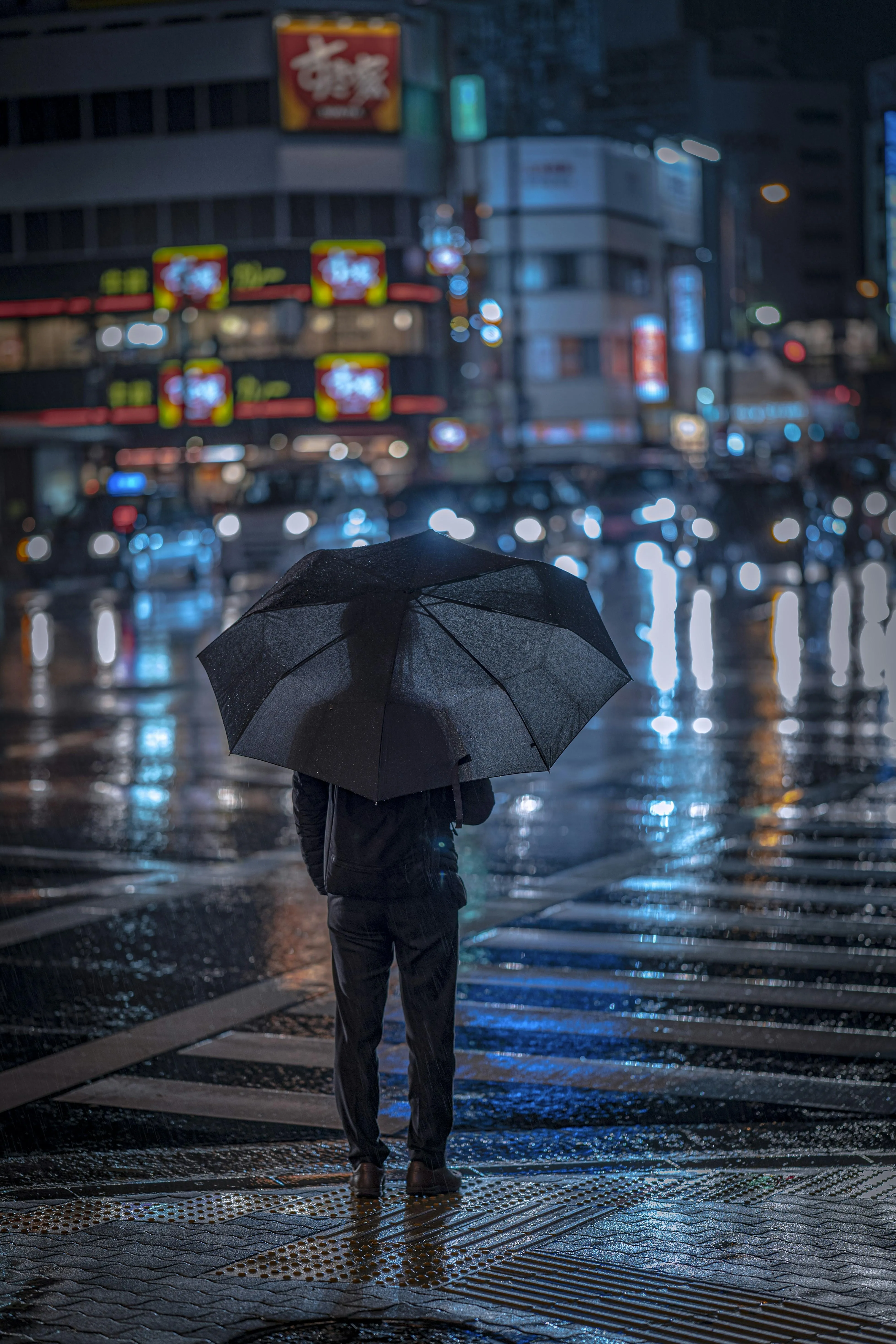 Man Holding Umbrella in Rainy Urban Street with Neon Lights