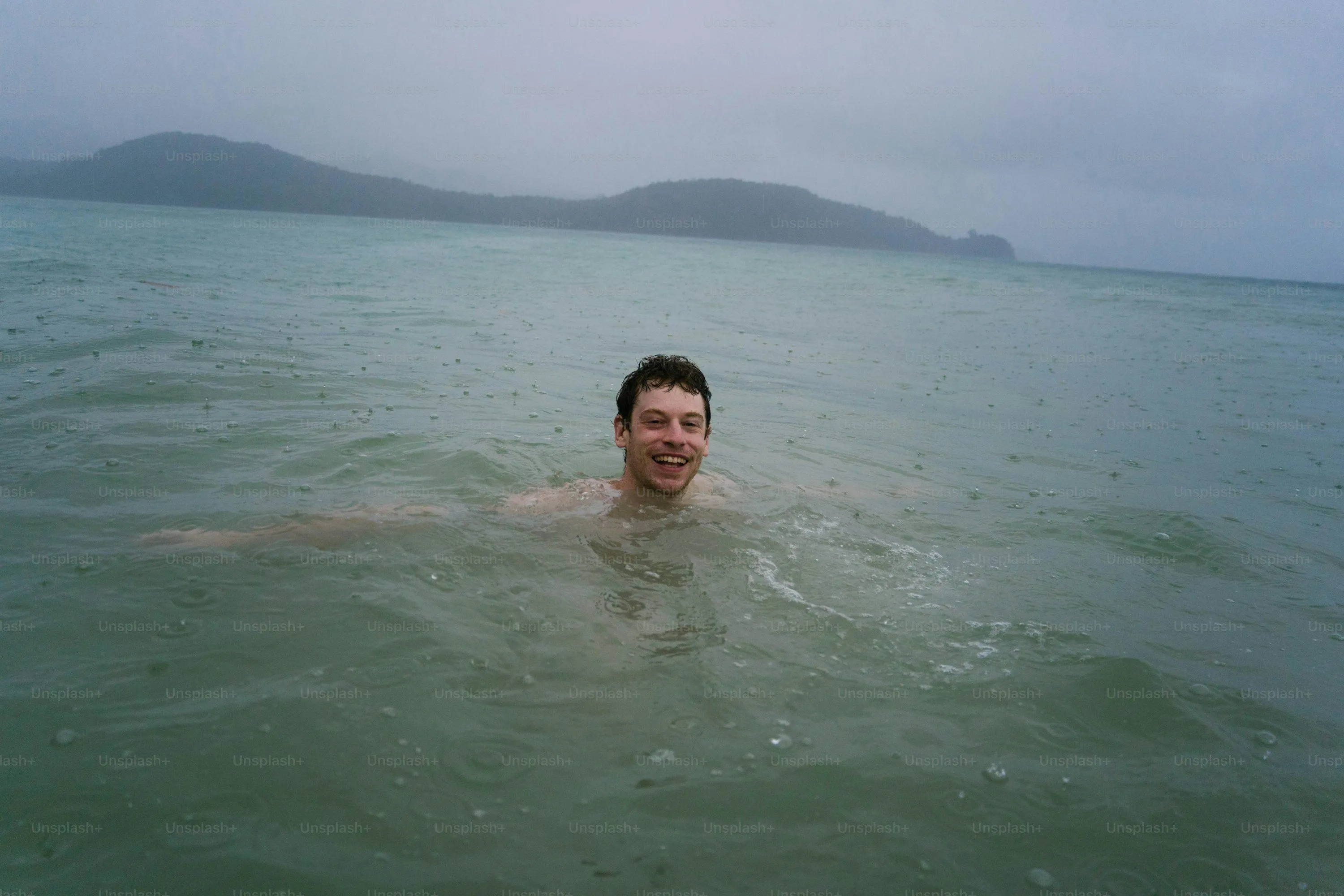 Man Swimming in Calm Sea Under Overcast Sky
