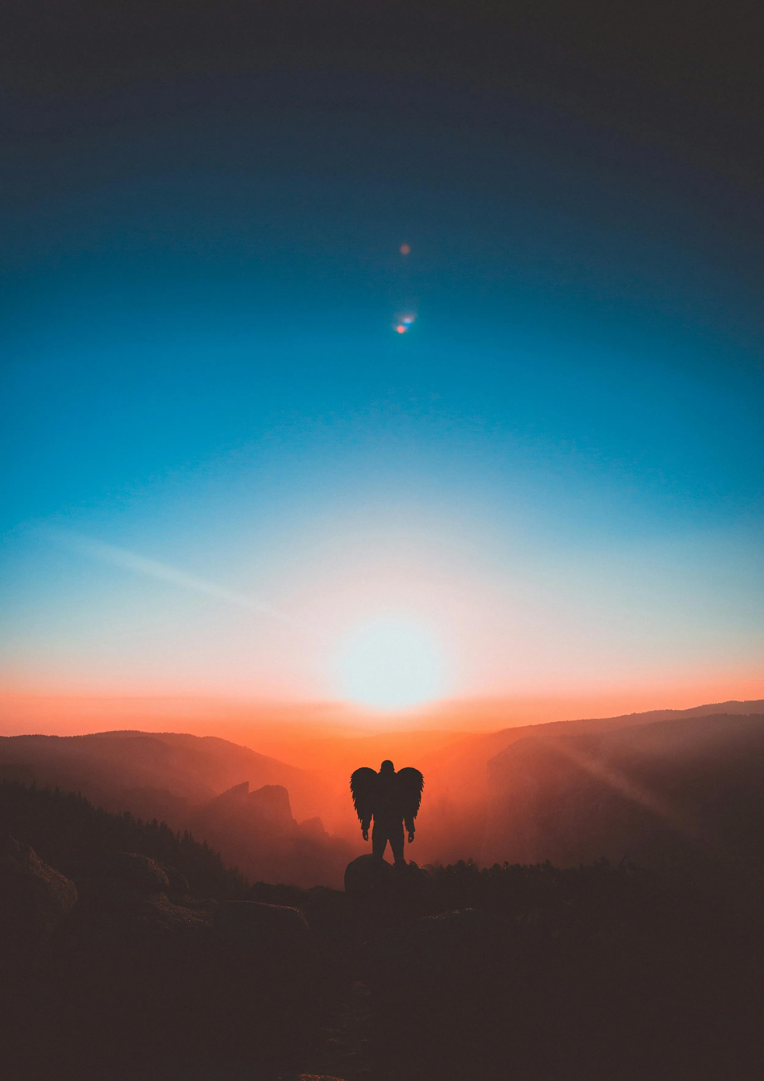 Man with Wings Silhouetted Against Sunrise on Mountain
