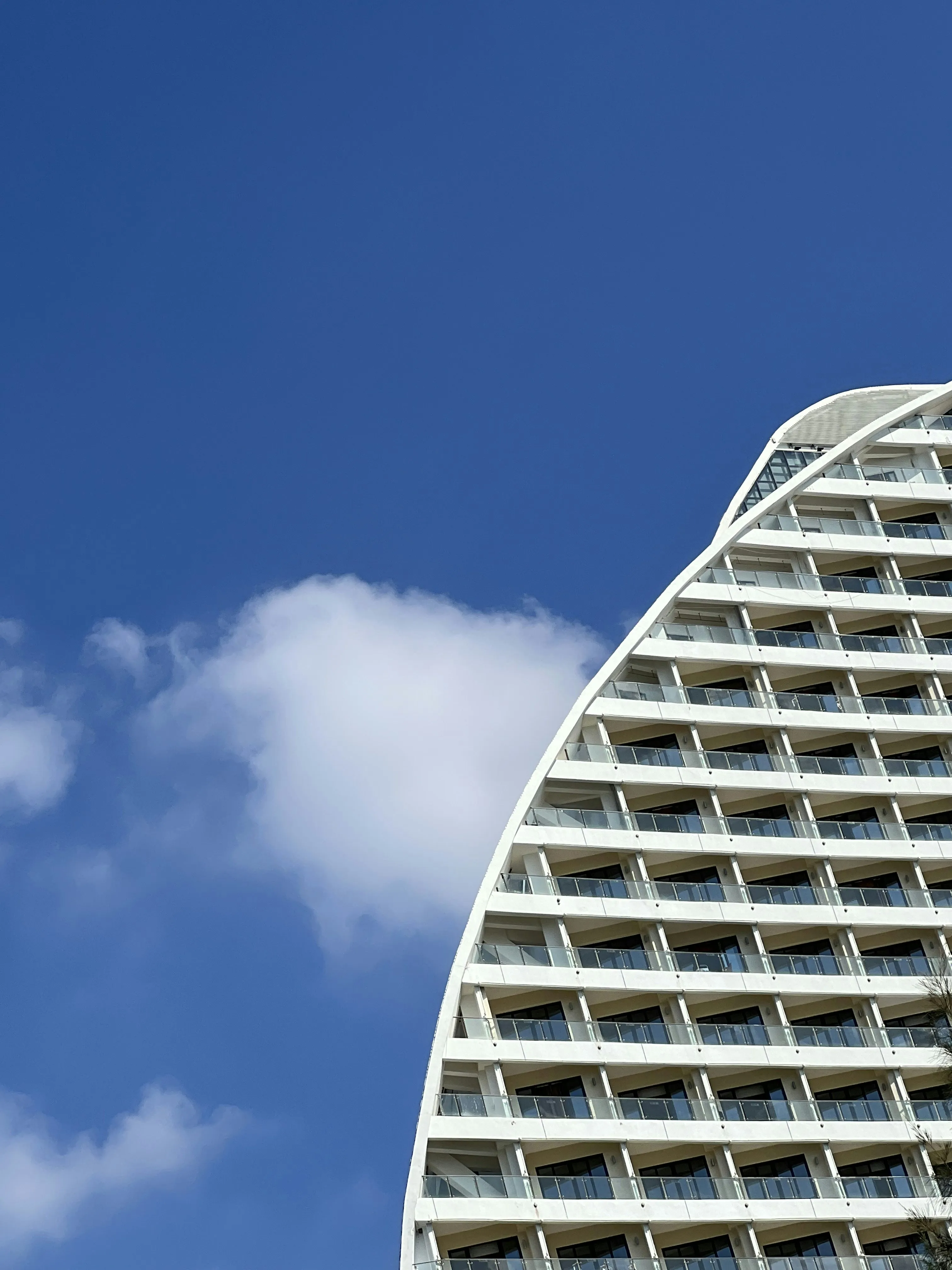 Modern Building with Curved Design Against Blue Cloudy Sky