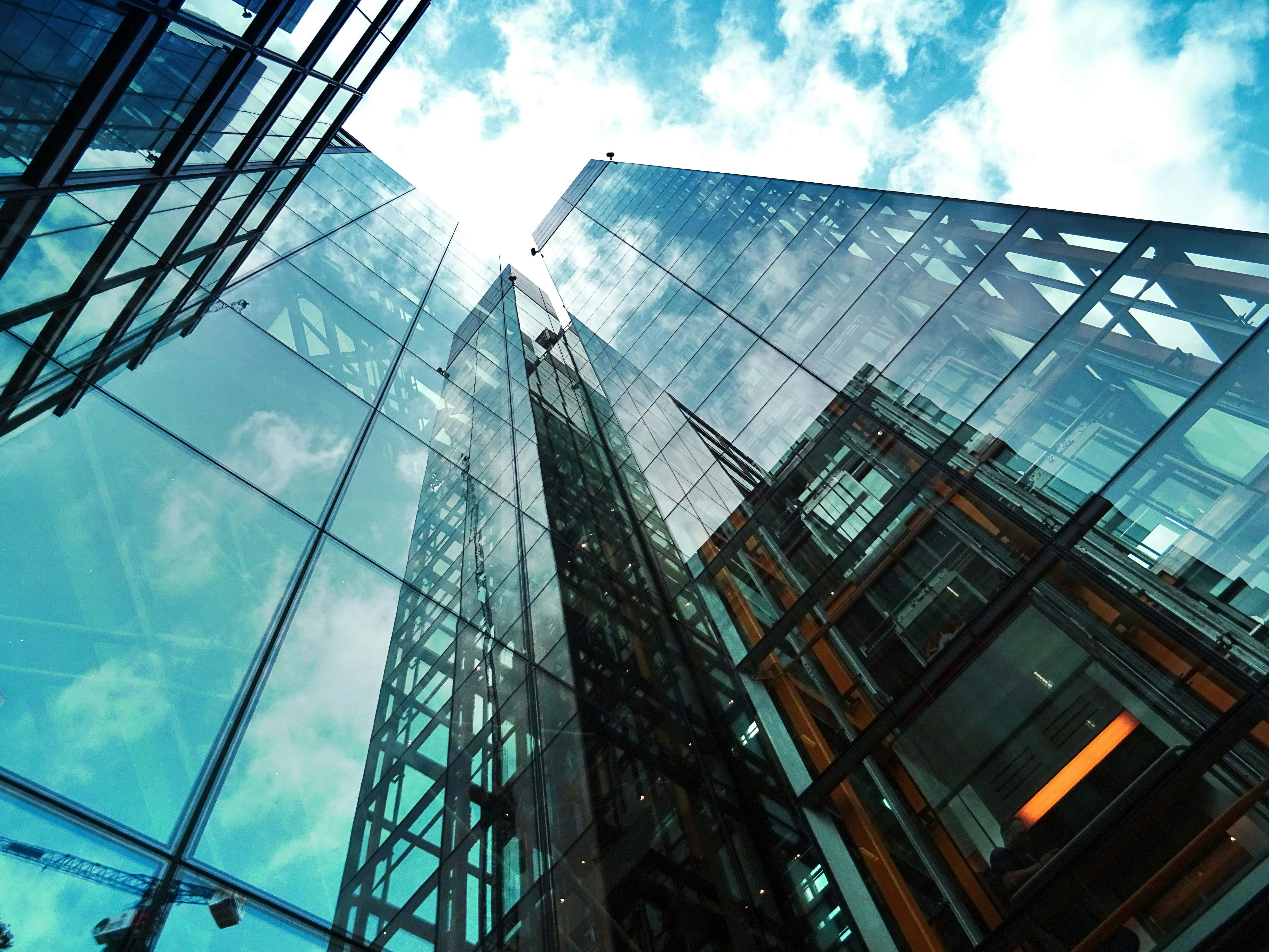 Modern Glass Building Reflecting Blue Sky and Clouds Above