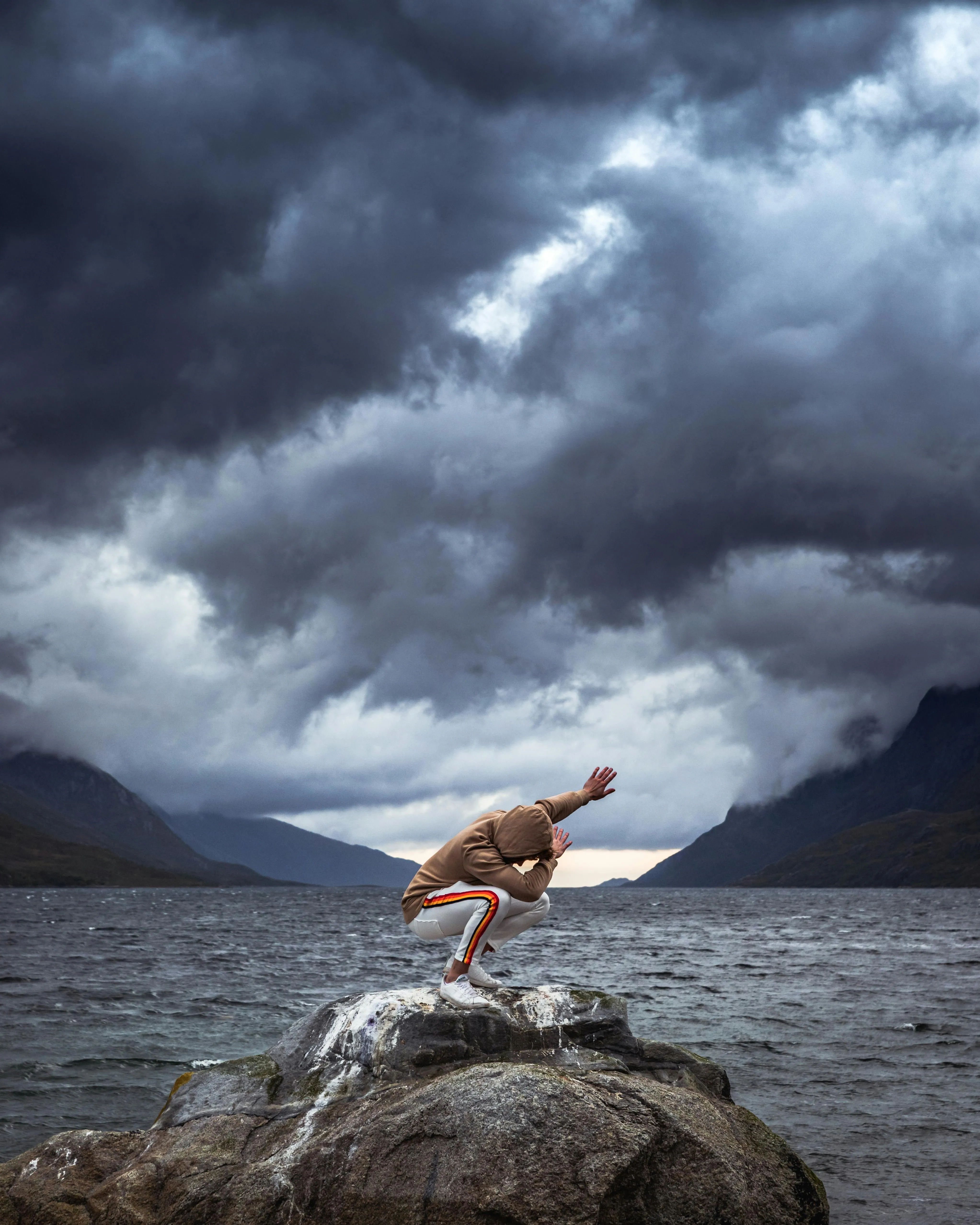 Moody Clouds Over Lake with Person Standing on Rock